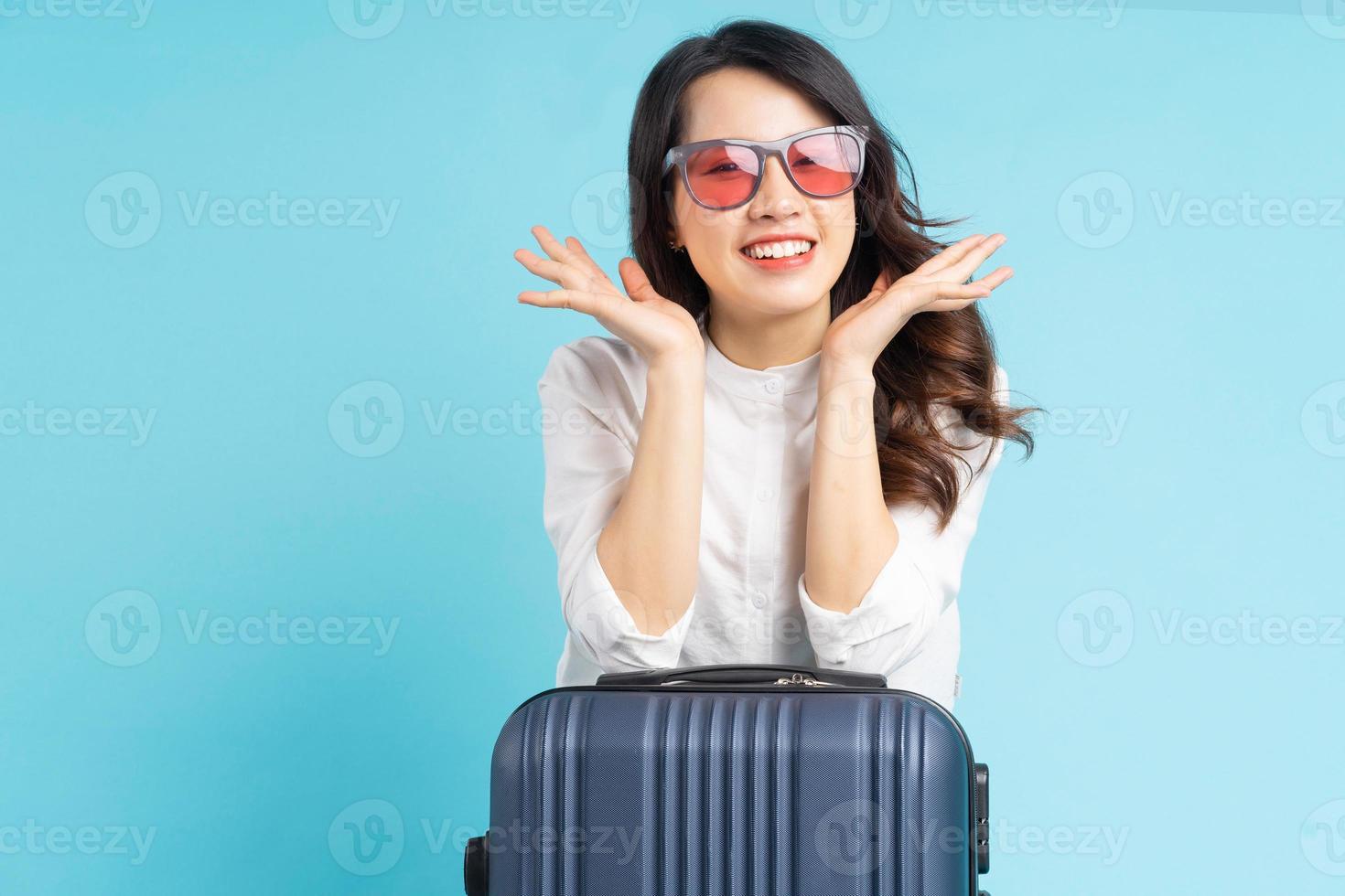 Hermosa mujer asiática sentada posando junto a la maleta y preparándose para viajar foto