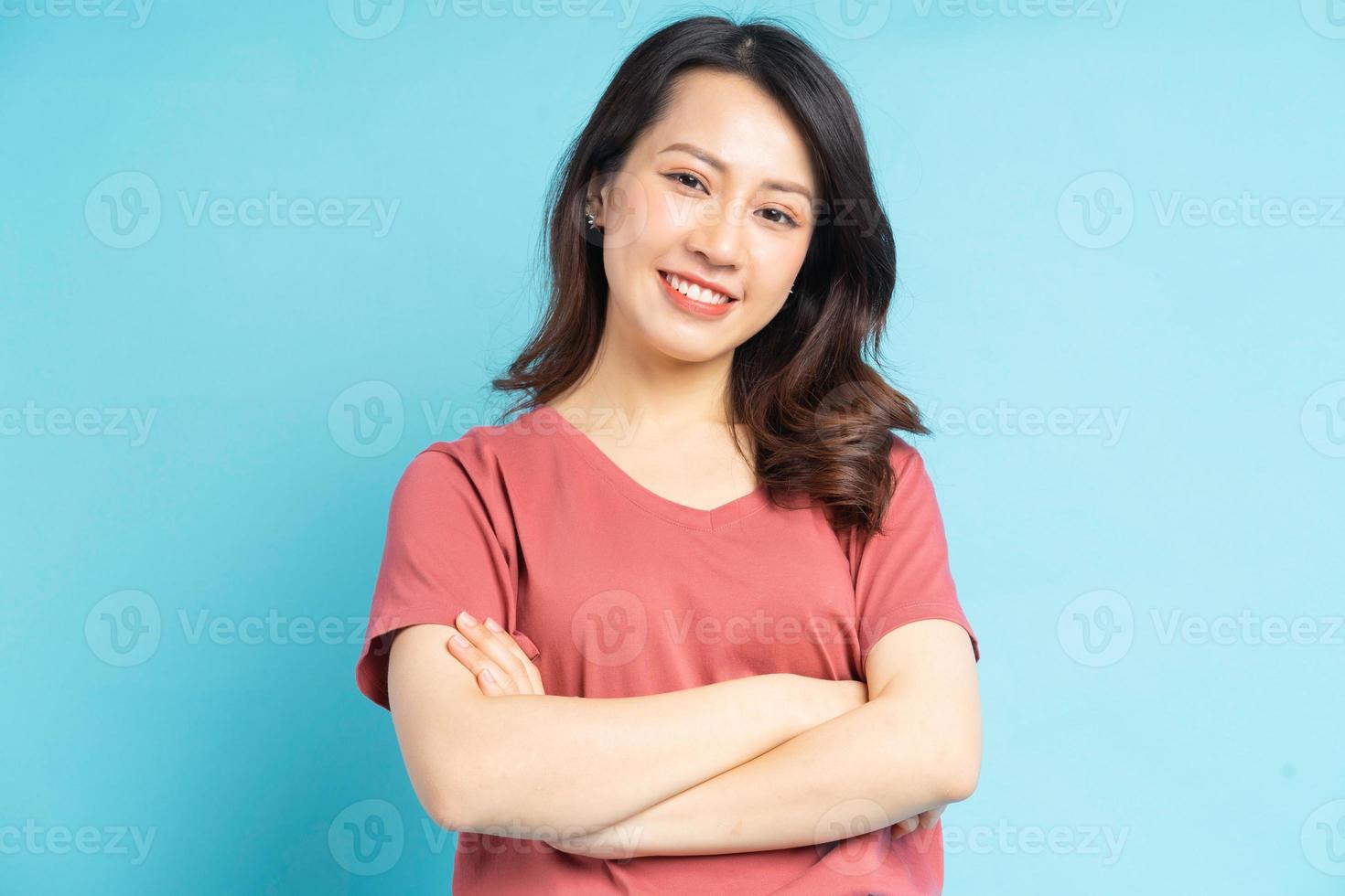 Hermosa mujer asiática con los brazos cruzados sobre fondo azul. foto