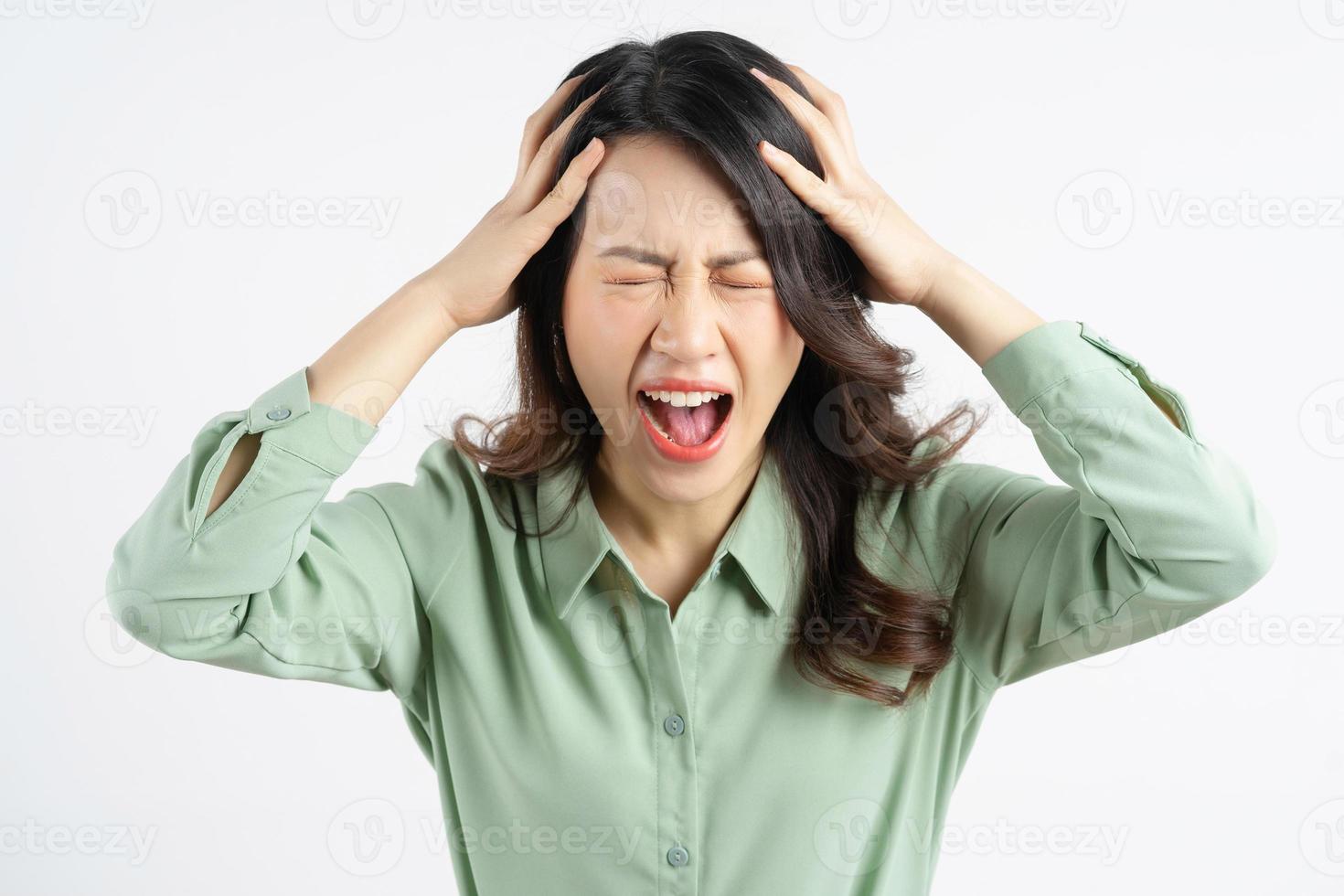Portrait of a beautiful Asian businesswoman holding her head and screaming photo