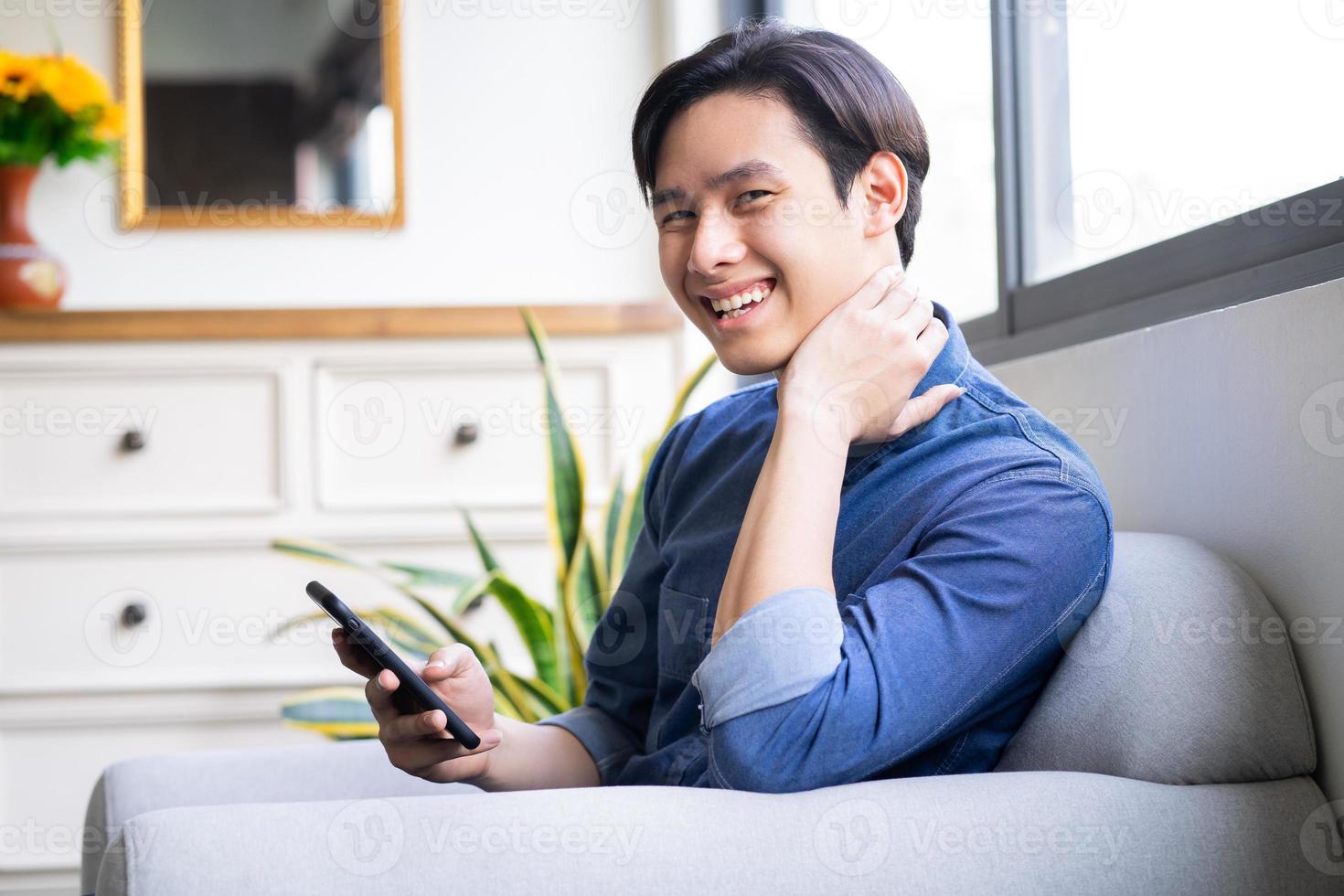 Young Asian man using the phone in the living room photo