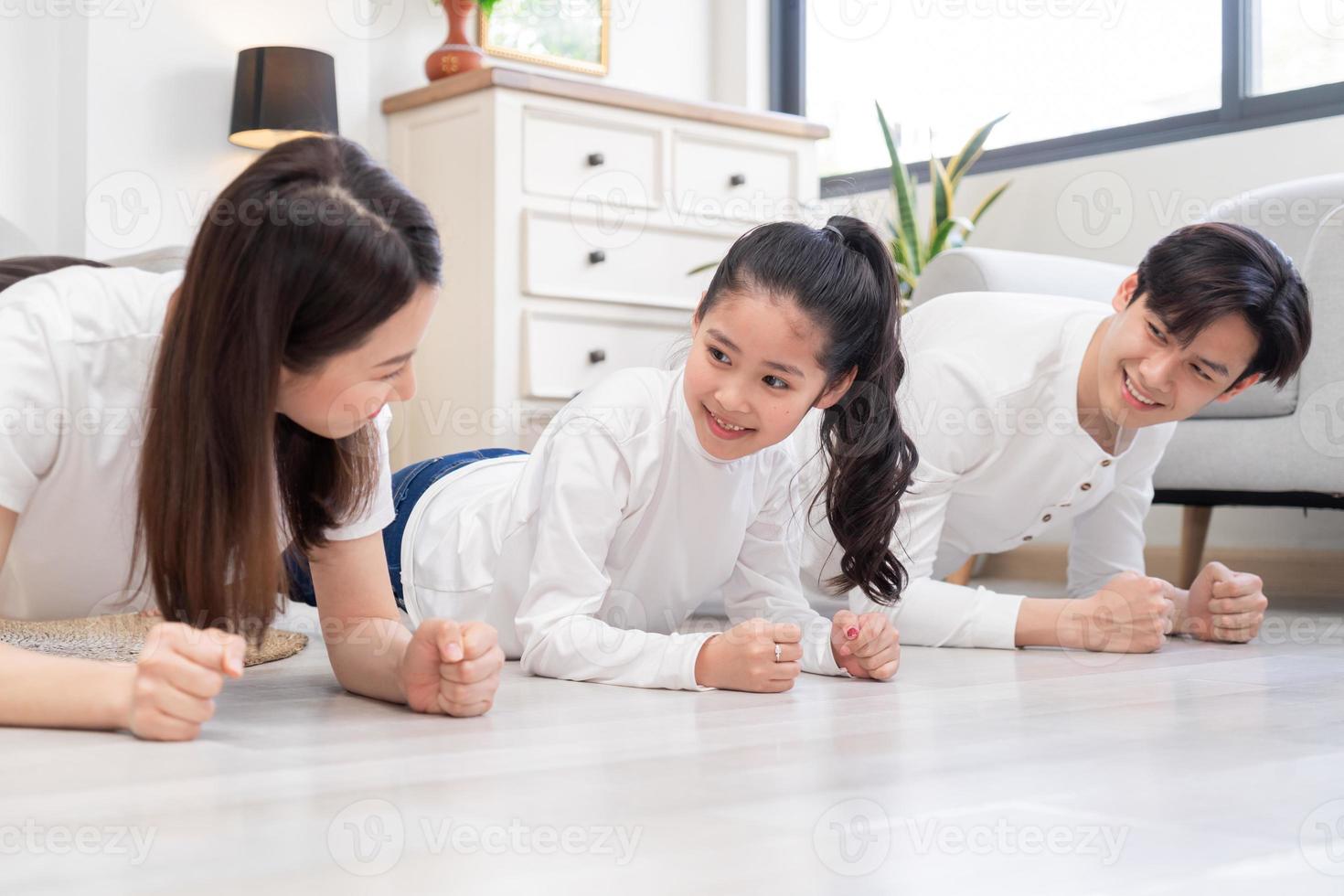 joven familia asiática haciendo ejercicio juntos en casa foto