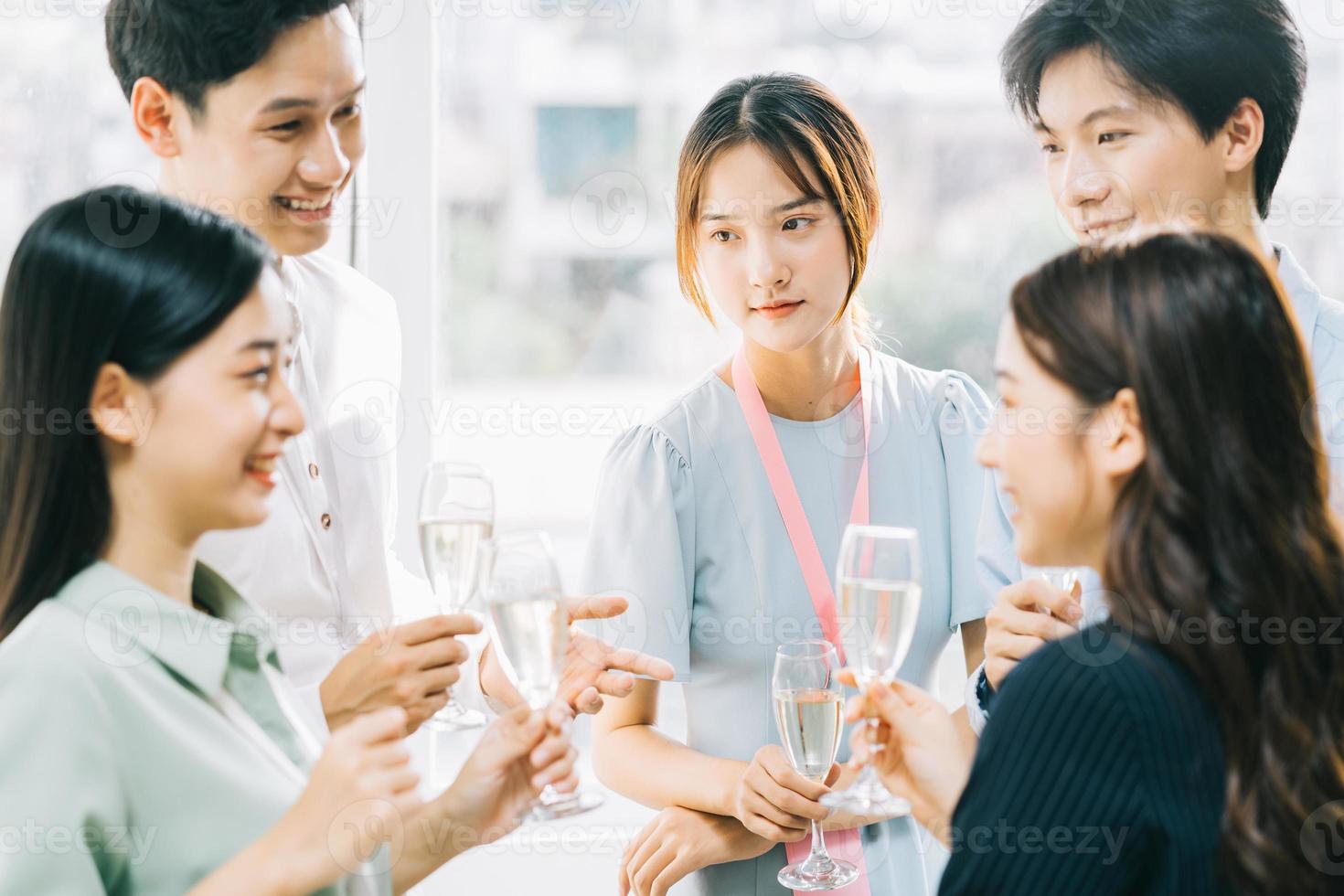 Grupo de empresarios asiáticos brindan juntos y charlan en una fiesta de la empresa foto