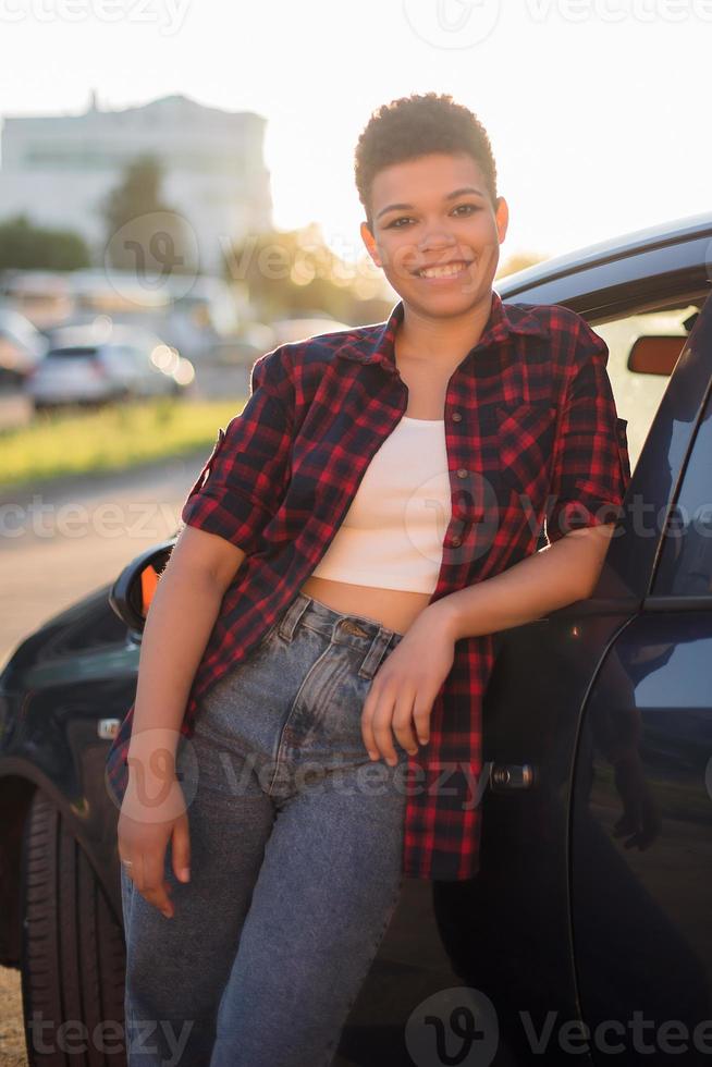 Beautiful African American woman with short hair near the car, lifestyle photo