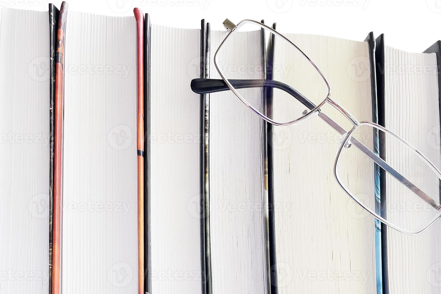 Glasses and thick books on a white background photo