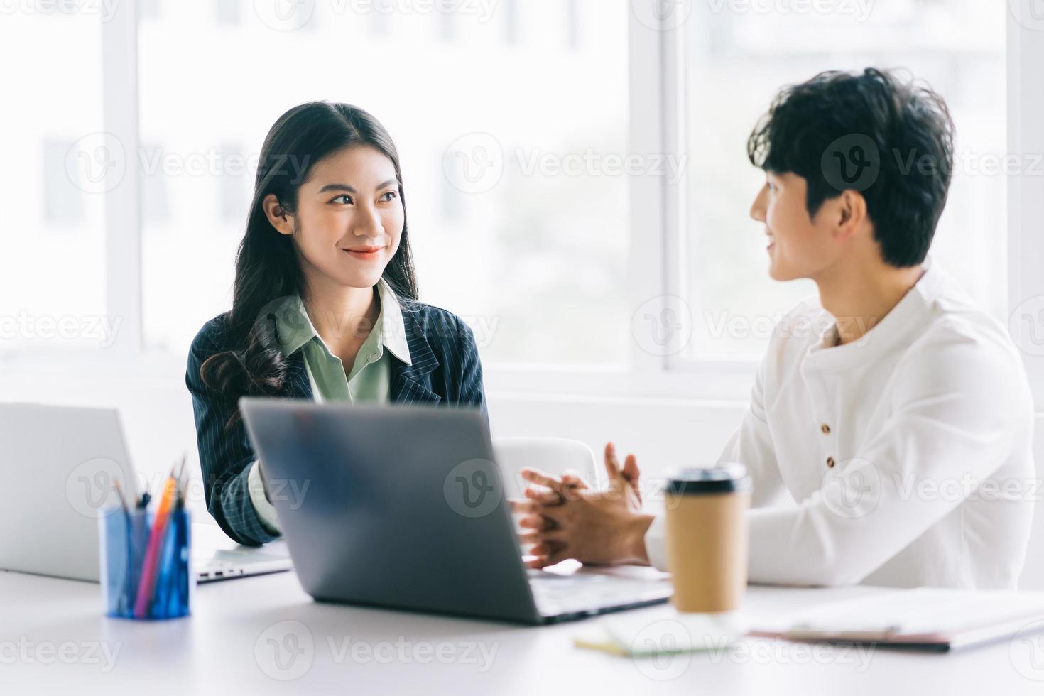 Two young Asian businessmen are discussing the year-end project photo