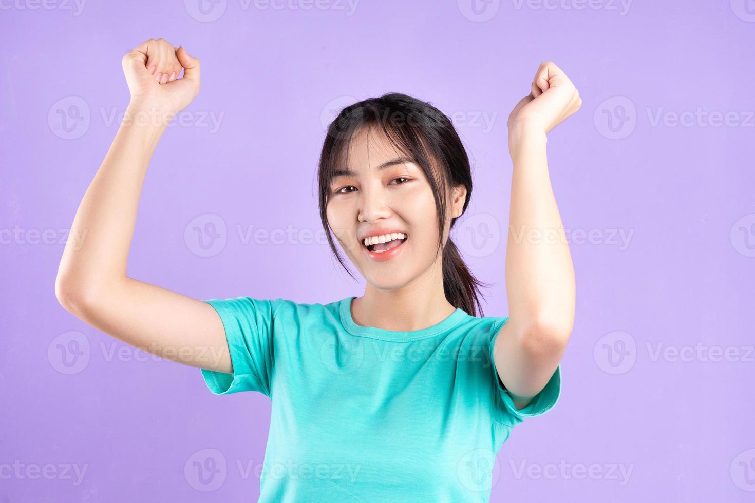 Young Asian girl in cyan shirt on purple background photo