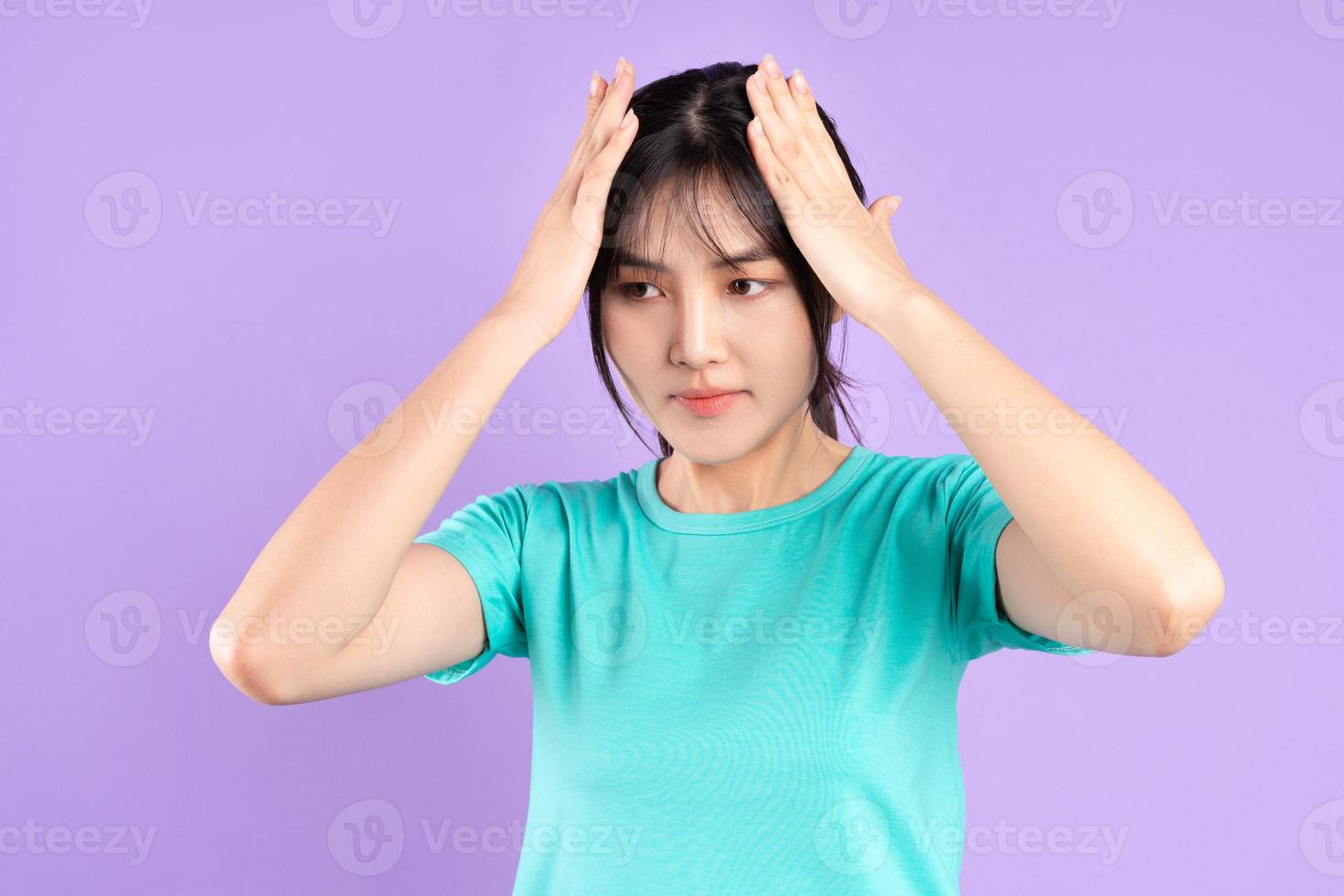 Young Asian girl in cyan shirt on purple background photo