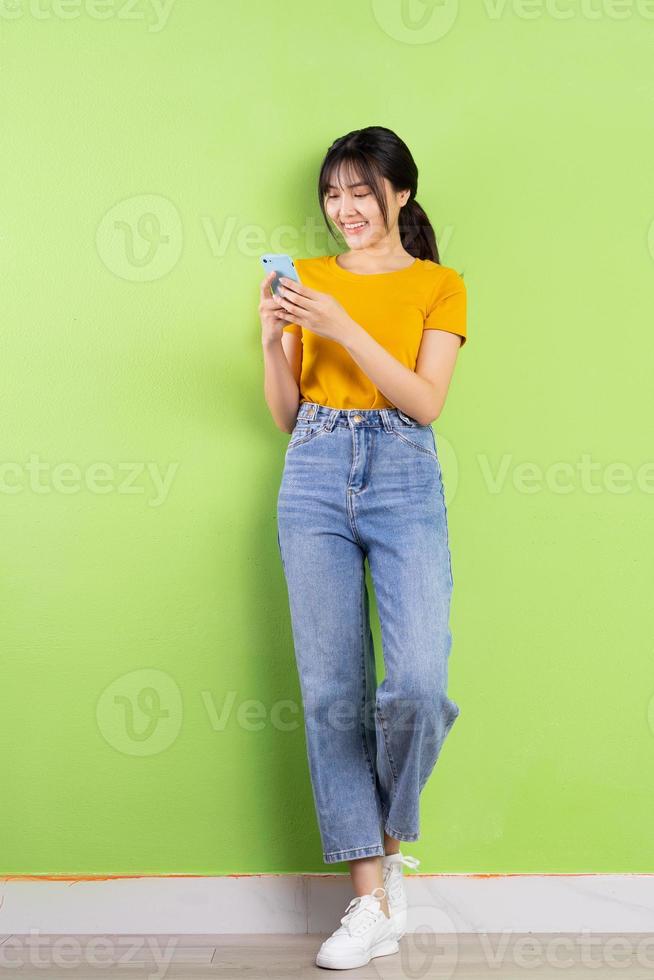 Full body portrait of young Asian girl on green background photo