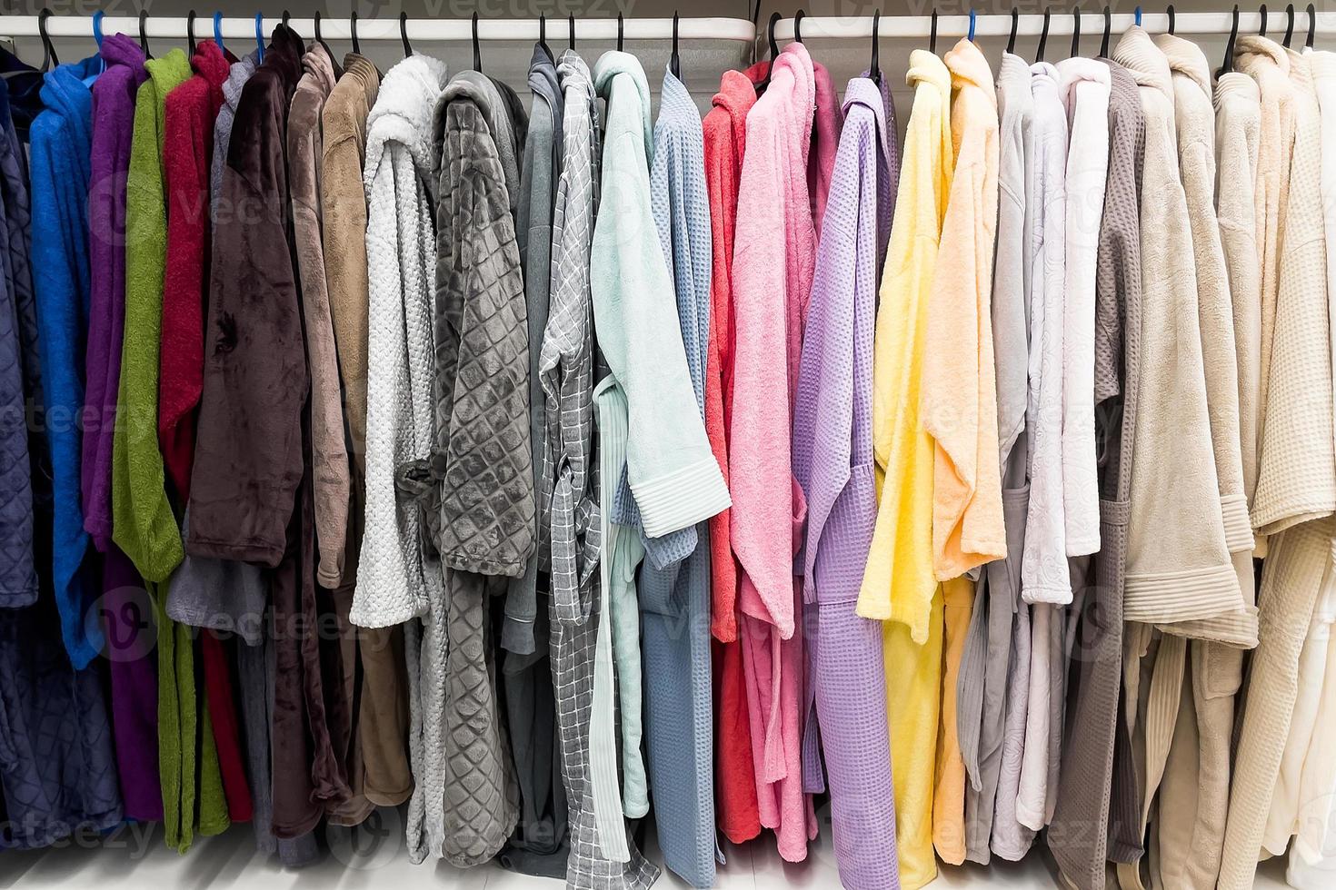 Different colored bathrobes on the hanger in the shower room photo