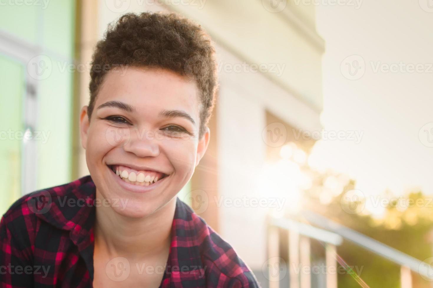 Hermosa y feliz mujer afroamericana con un corte de pelo corto en el verano en la calle foto