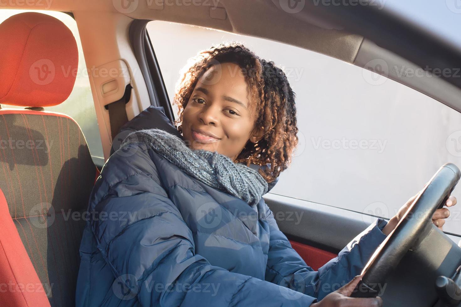 Feliz mujer afroamericana en un automóvil, otoño-invierno foto