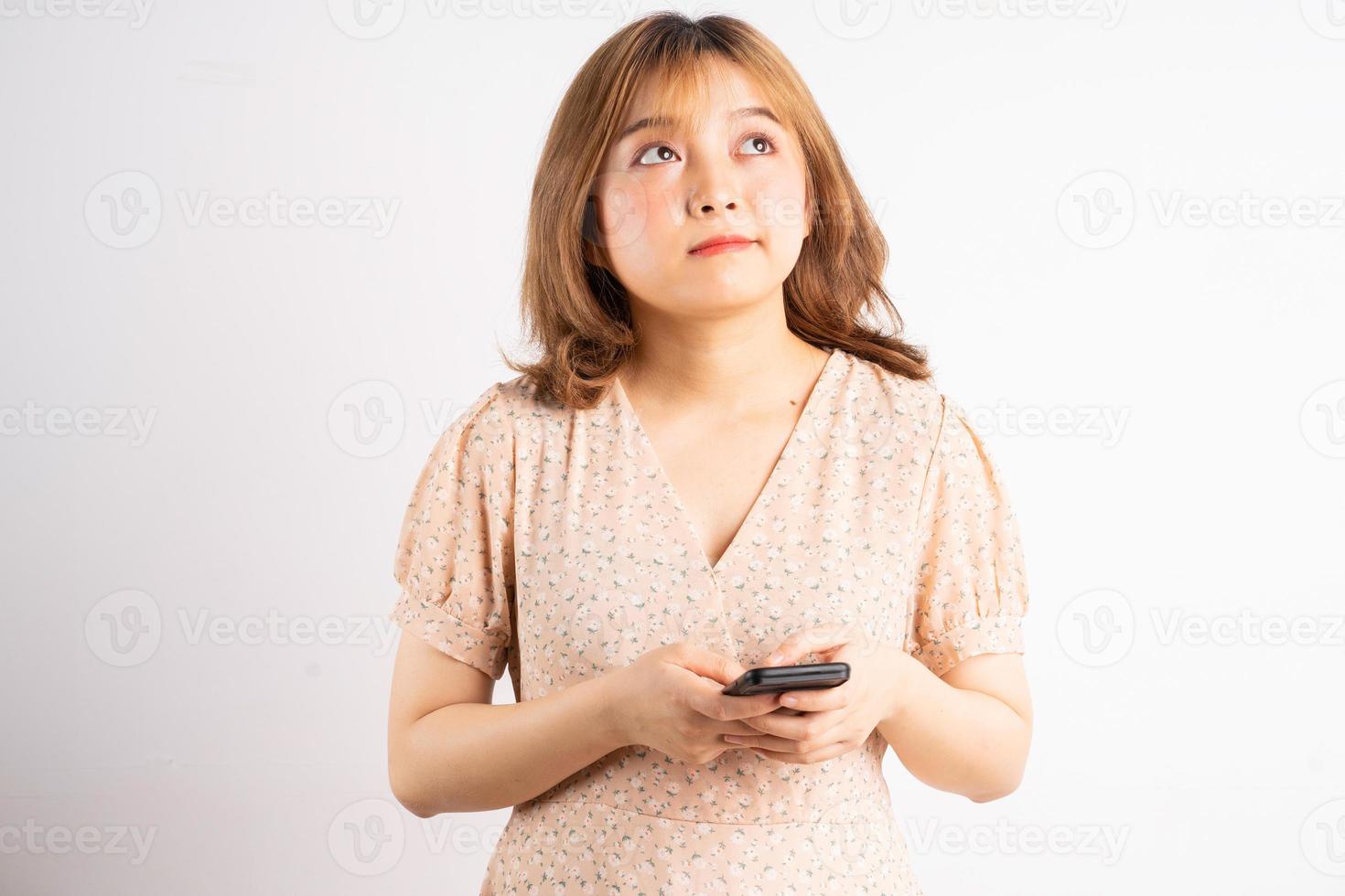 Young Asian girl holding phone with expressions, gestures on background photo