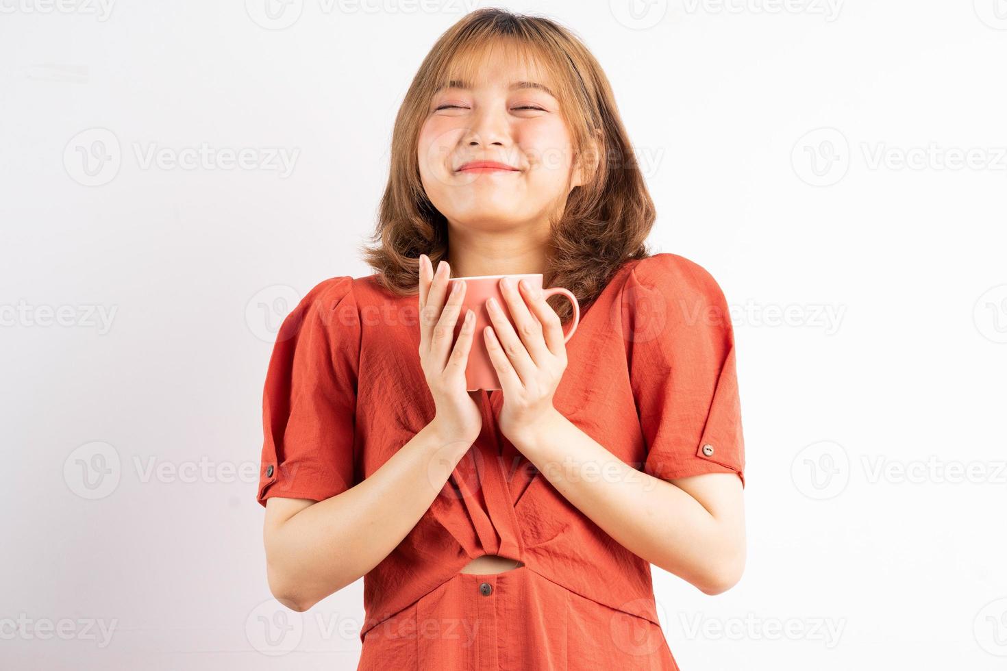 Niña sosteniendo la taza de café con expresión feliz sobre fondo blanco. foto