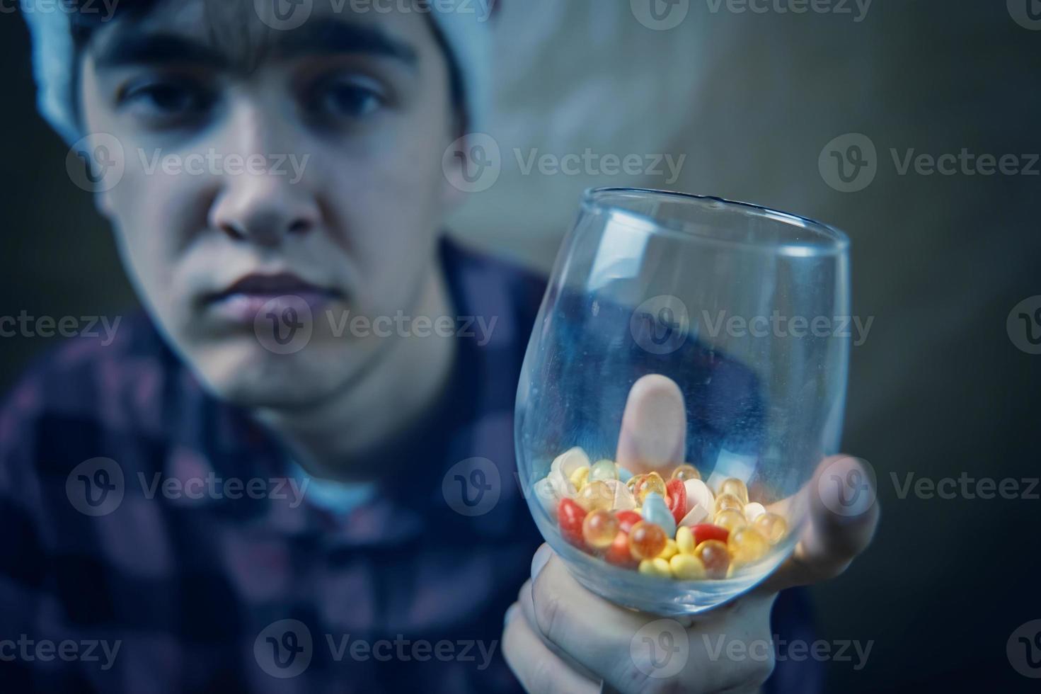 Sad guy holding a glass of pills and medicines. photo
