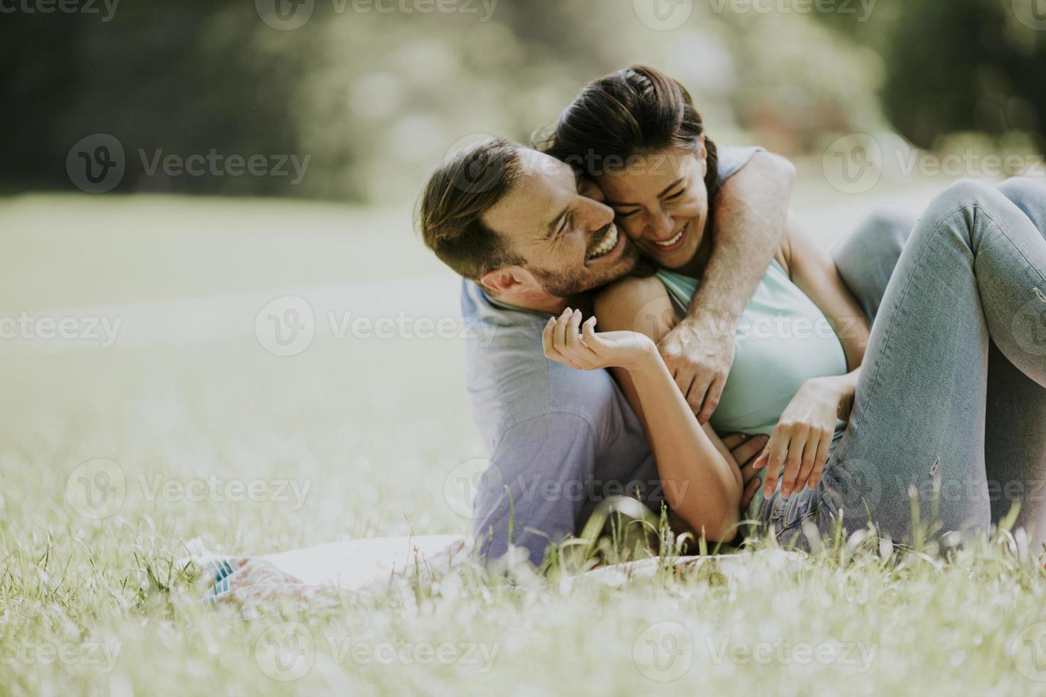 Afectuosa pareja joven sentada en la hierba verde foto