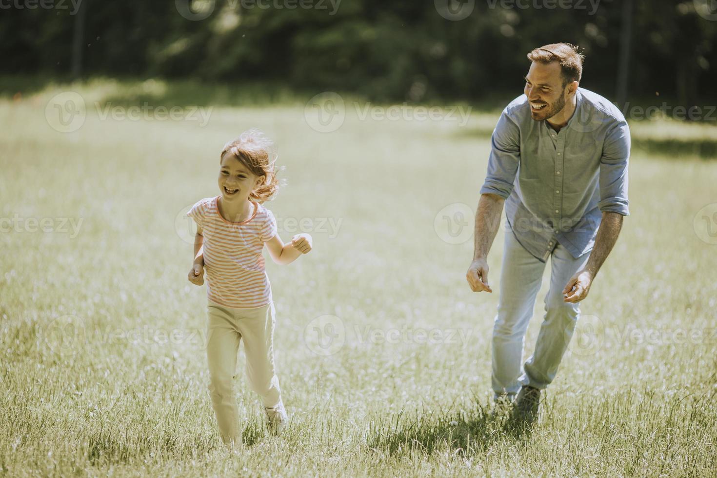 Father chasing his little daughter while playing in the park photo