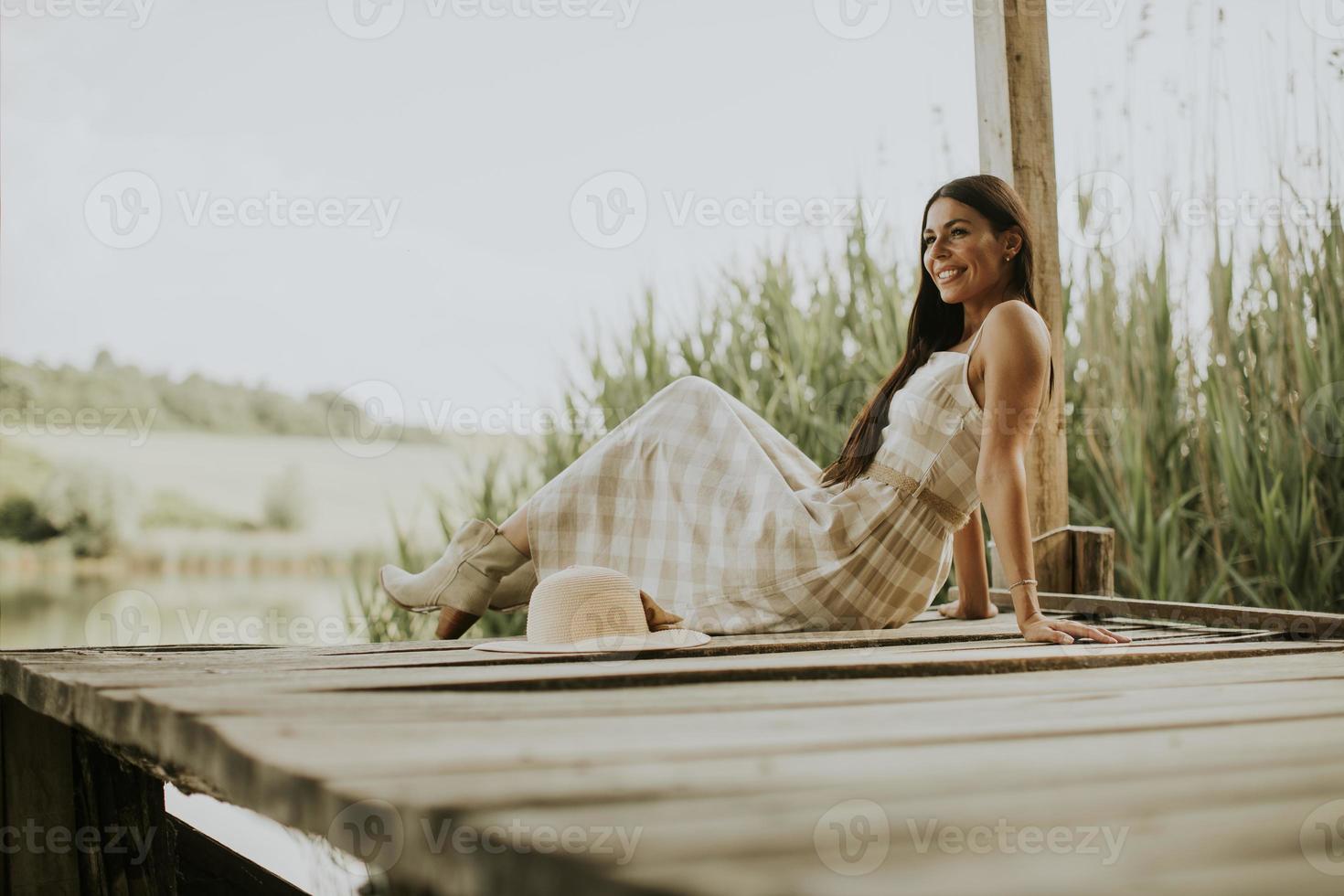 Relaxing young woman on wooden pier at the lake photo