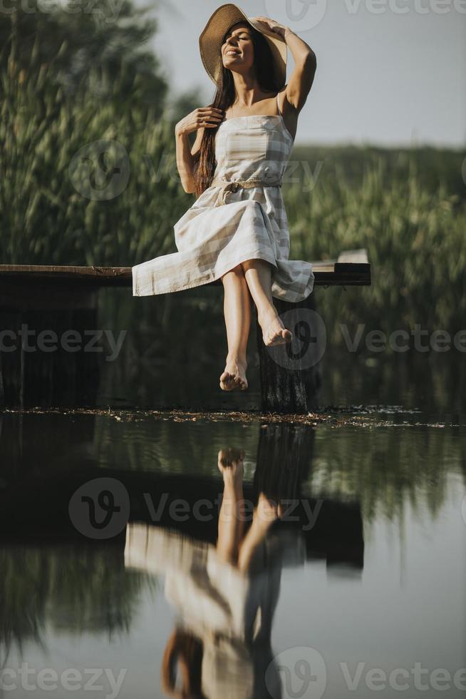 Relaxing young woman on wooden pier at the lake photo