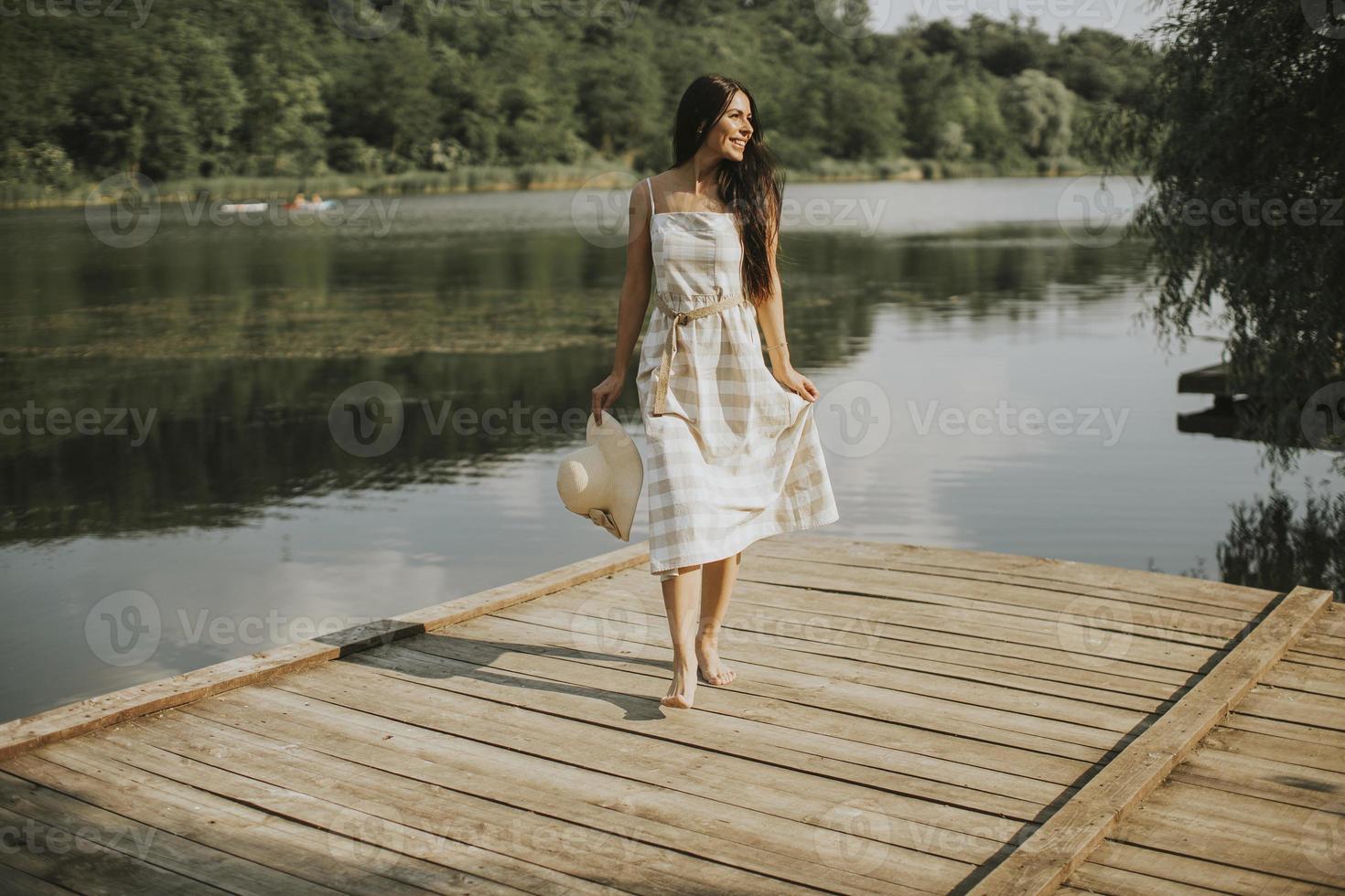 relajante, mujer joven, posición, en, muelle de madera, en el lago foto