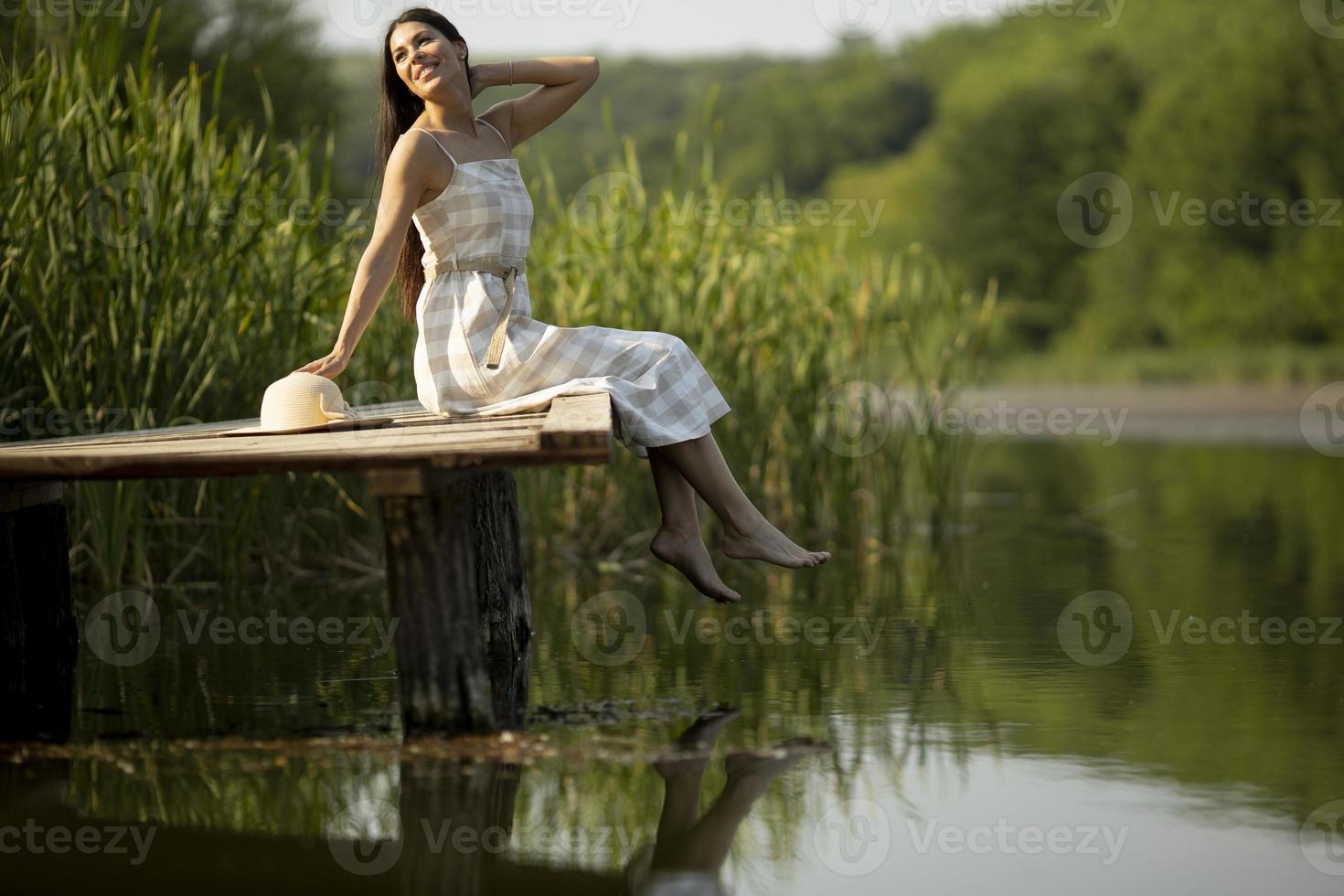 mujer joven relajante en el muelle de madera en el lago foto