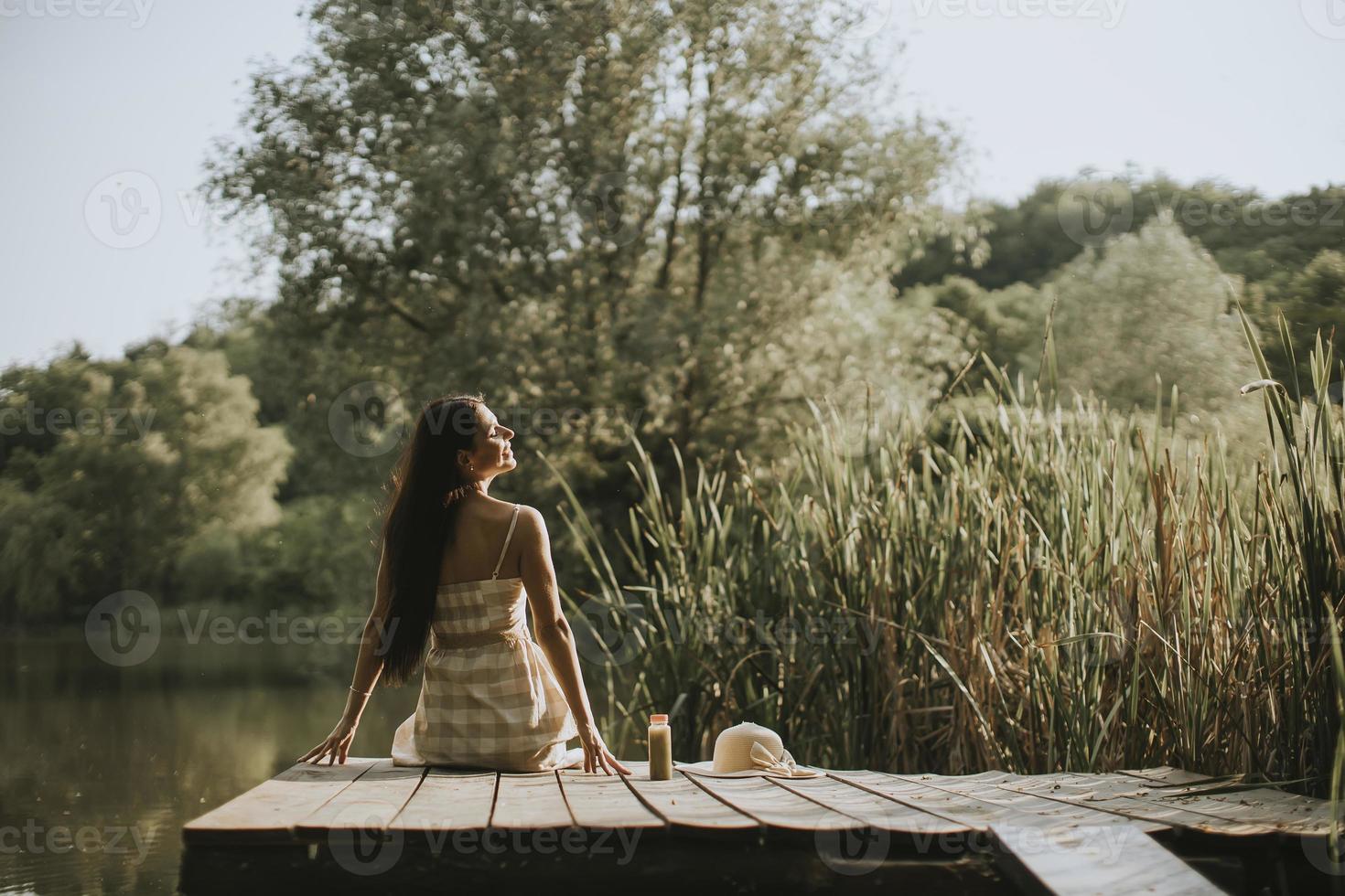 Relaxing young woman on wooden pier at the lake photo