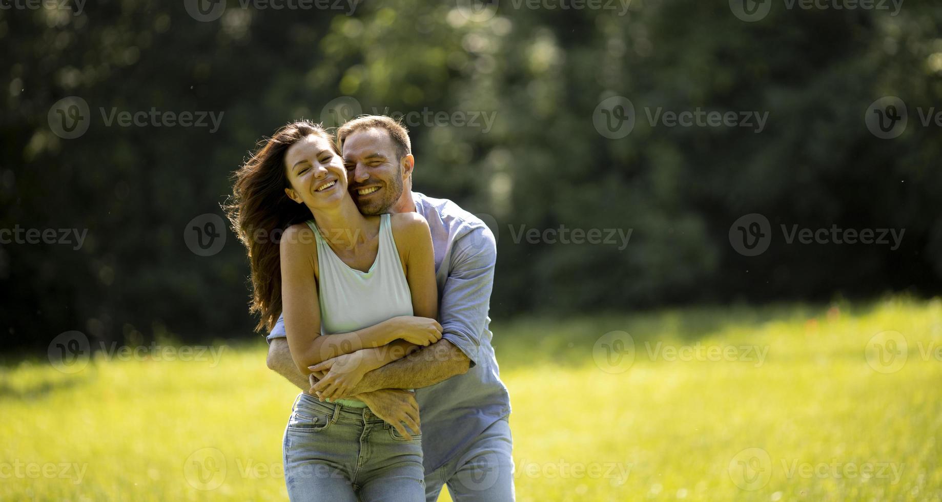 Afectuosa pareja joven divirtiéndose en la hierba verde foto