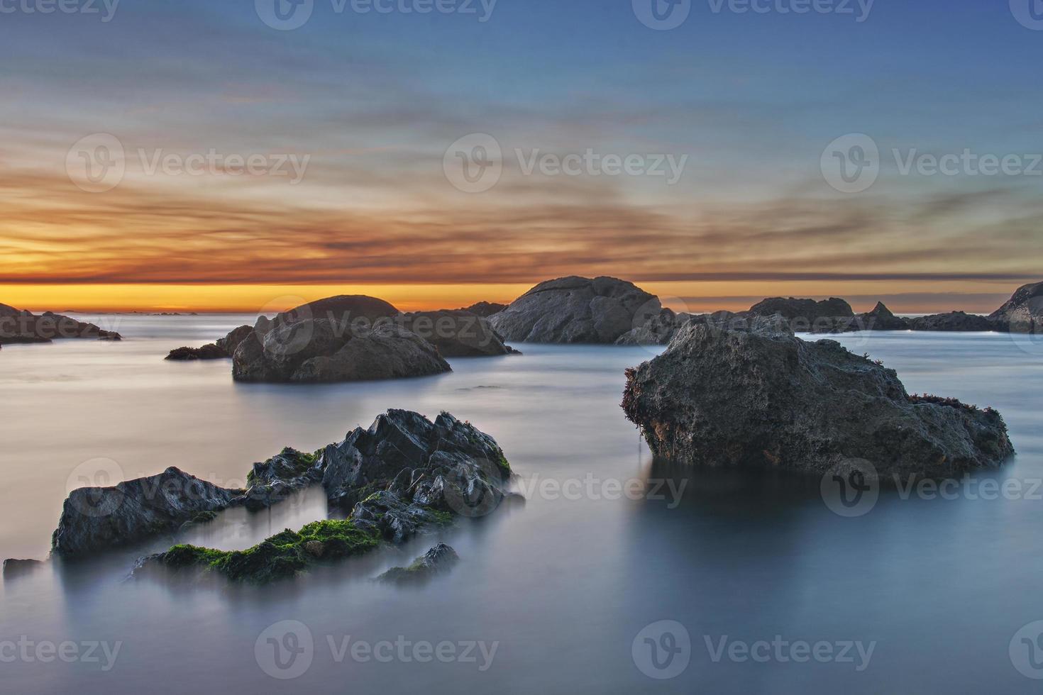 Calm beach with rocks at sunset photo