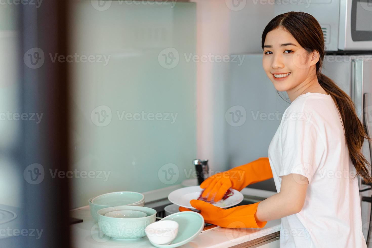 la mujer asiática está lavando los platos foto