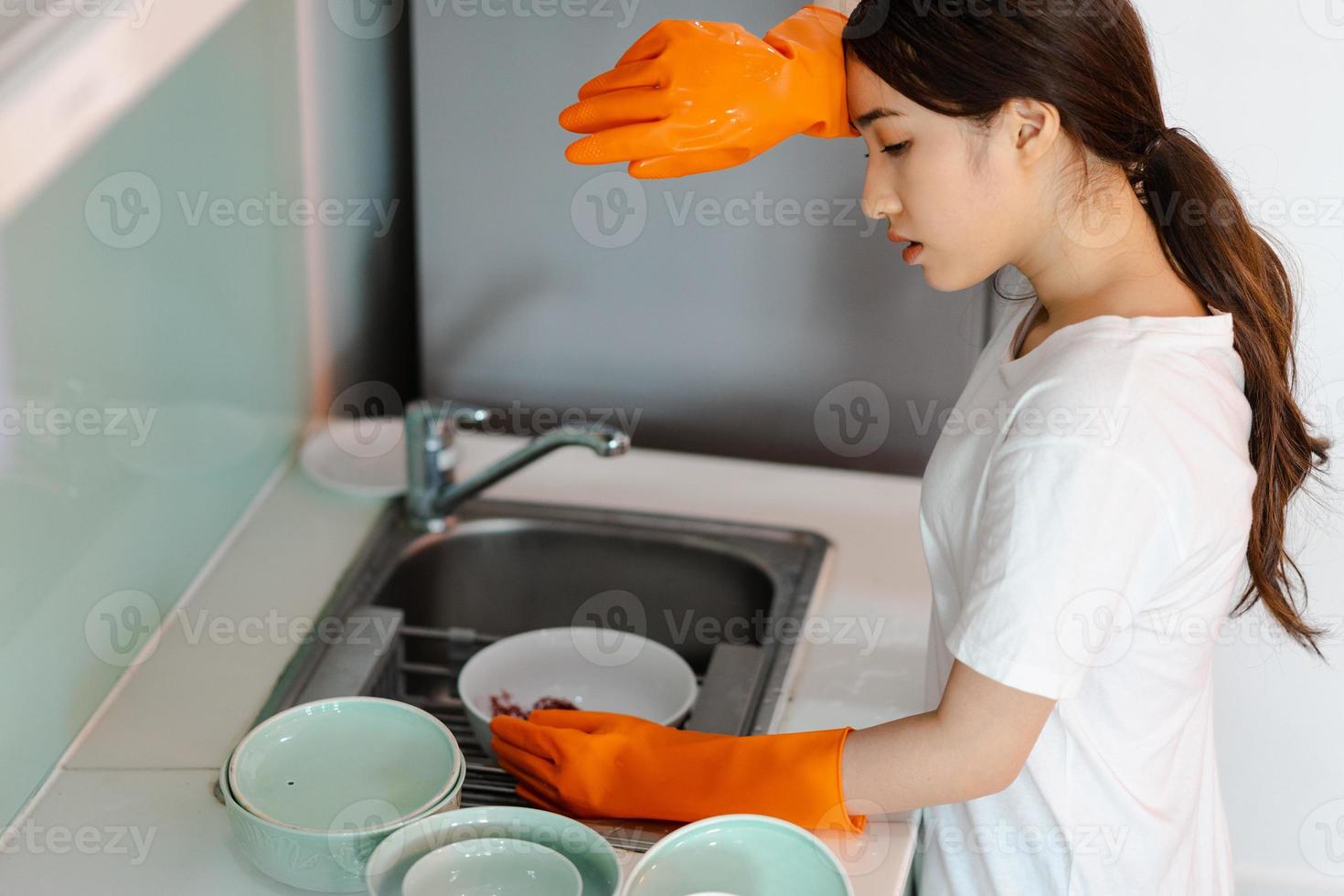 la mujer asiática está lavando platos en un estado de ánimo cansado foto