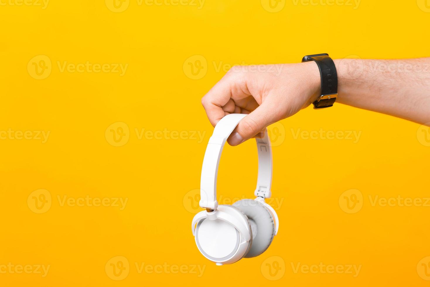Close up photo of male hand holding white wireless headphones
