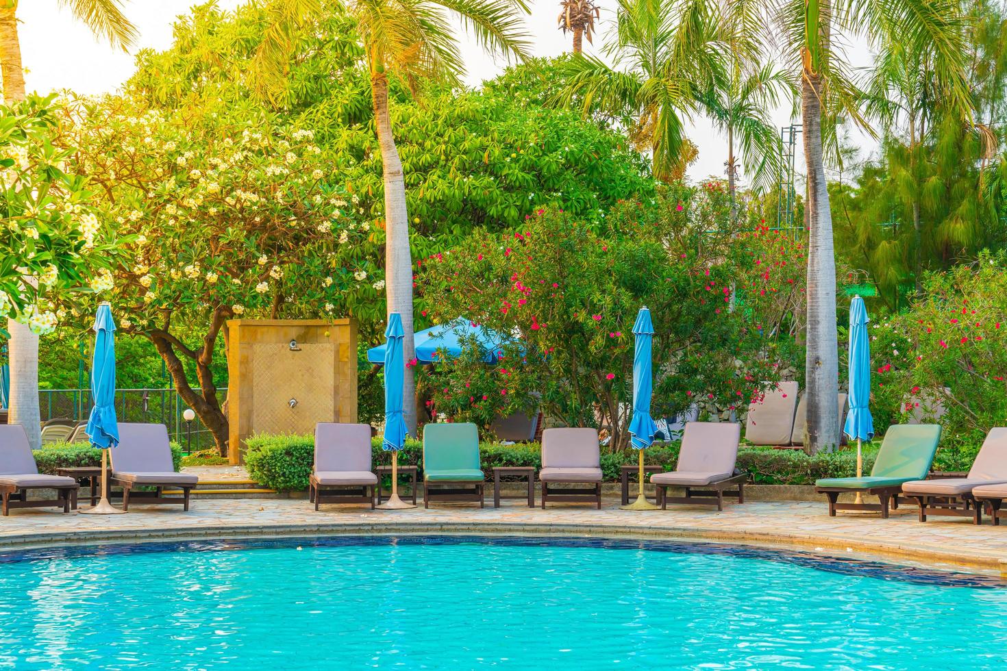 Beach chairs or pool beds with umbrellas around swimming pool at sunset time photo