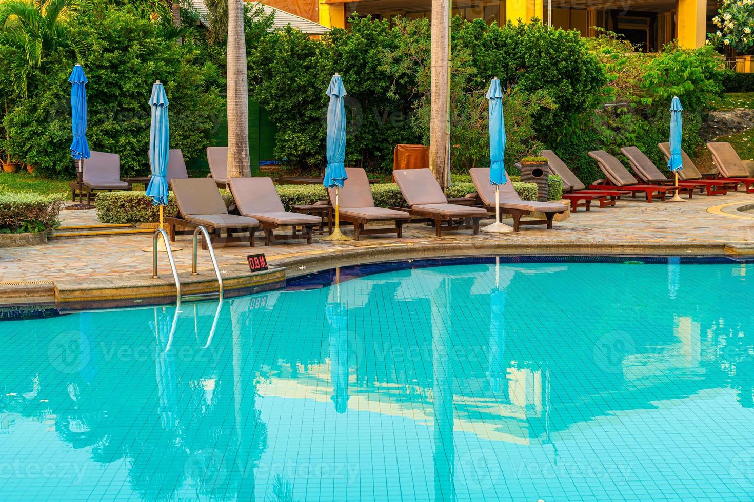 Beach chairs or pool beds with umbrellas around swimming pool at sunset time photo