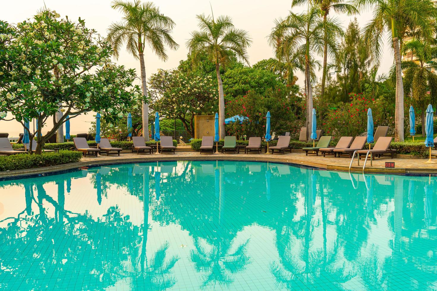 Beach chairs or pool beds with umbrellas around swimming pool at sunset time photo