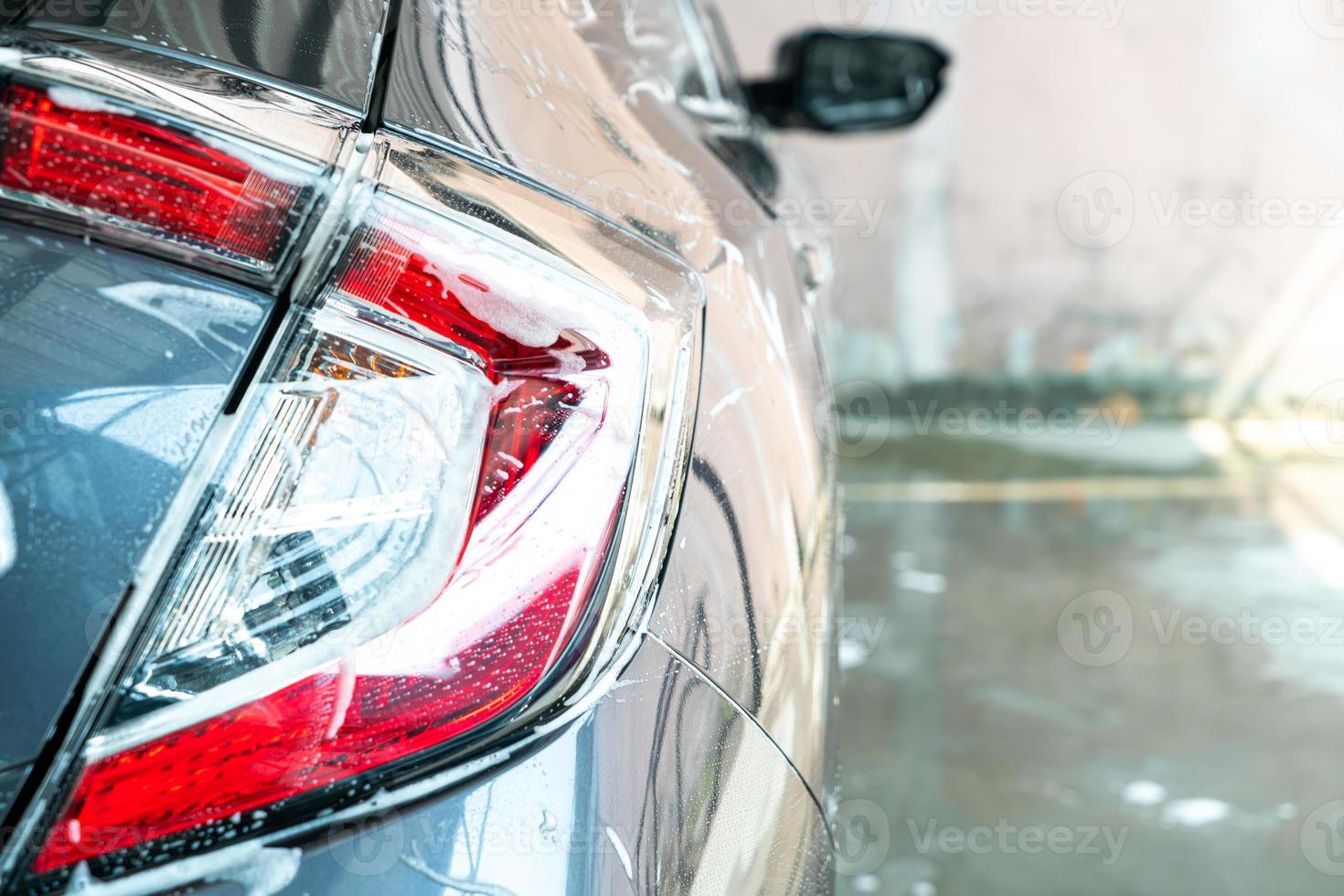 Lámpara de faro de coche de primer plano con espuma de lavado de coches foto