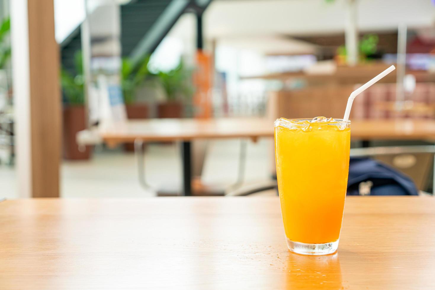 Jugo de naranja helado en la mesa de madera en el café restaurante foto