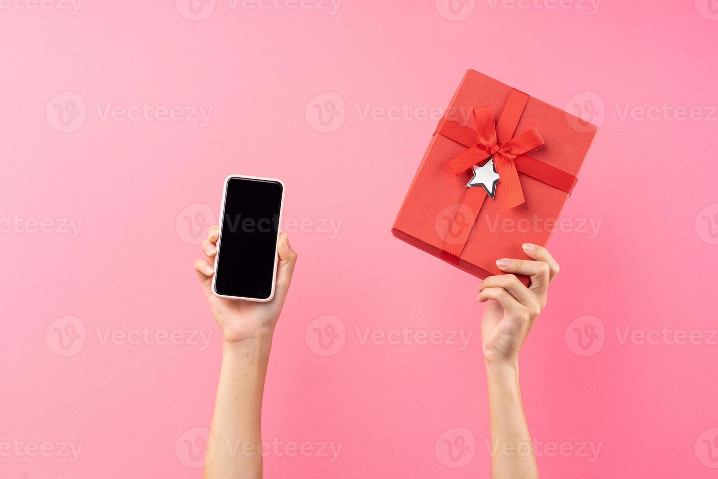 manos sosteniendo caja de regalo roja y teléfono foto