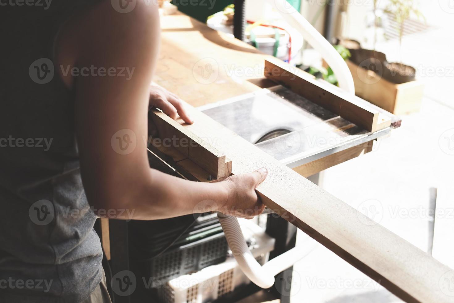 Los operadores de carpintería utilizan máquinas cortadoras de tablones para ensamblar y construir mesas de madera para los clientes. foto