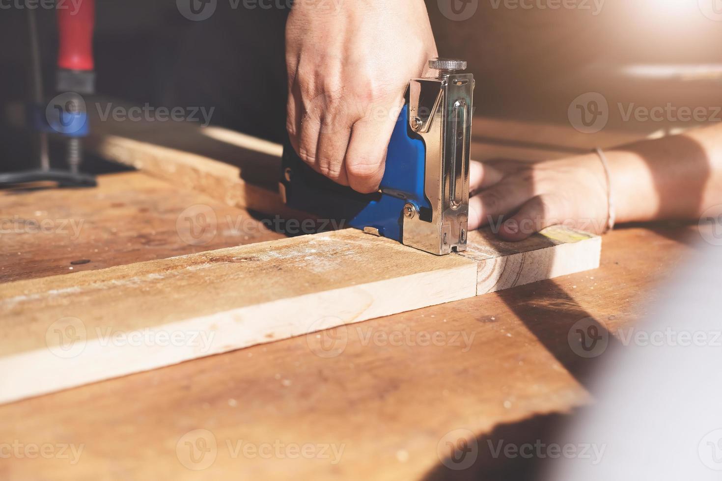 empresario de carpintería sosteniendo una grapadora para ensamblar las piezas de madera según lo ordenaba el cliente. foto