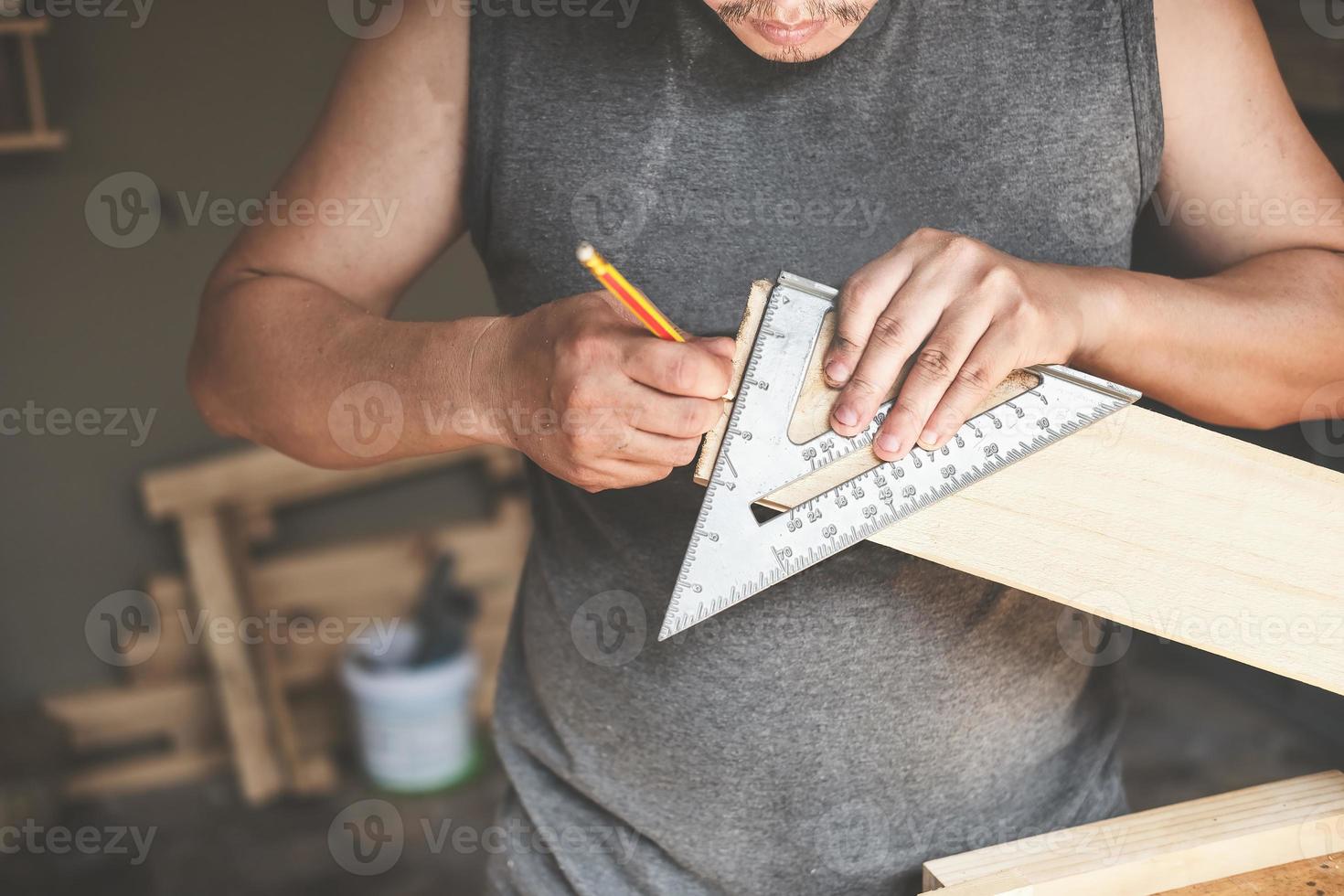 un carpintero mide las placas para ensamblar las piezas. y construir una mesa de madera para los clientes. foto