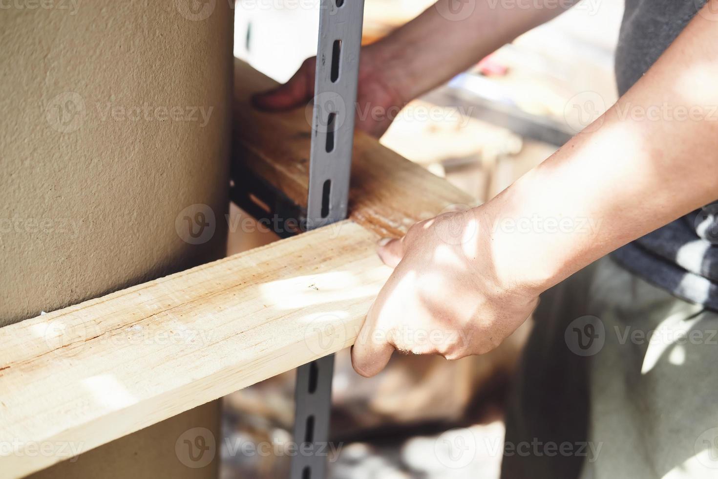 A carpenter measures the planks to assemble the parts, and build a wooden table for the customer. photo
