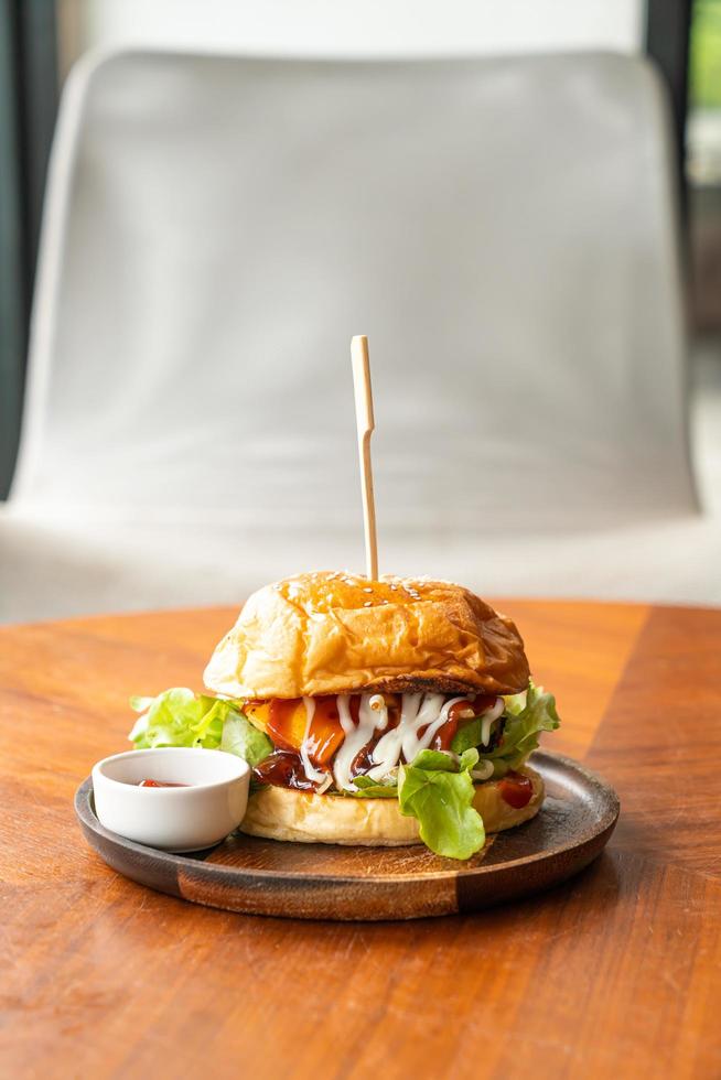 Hamburguesa de ternera con queso y salsa sobre placa de madera foto