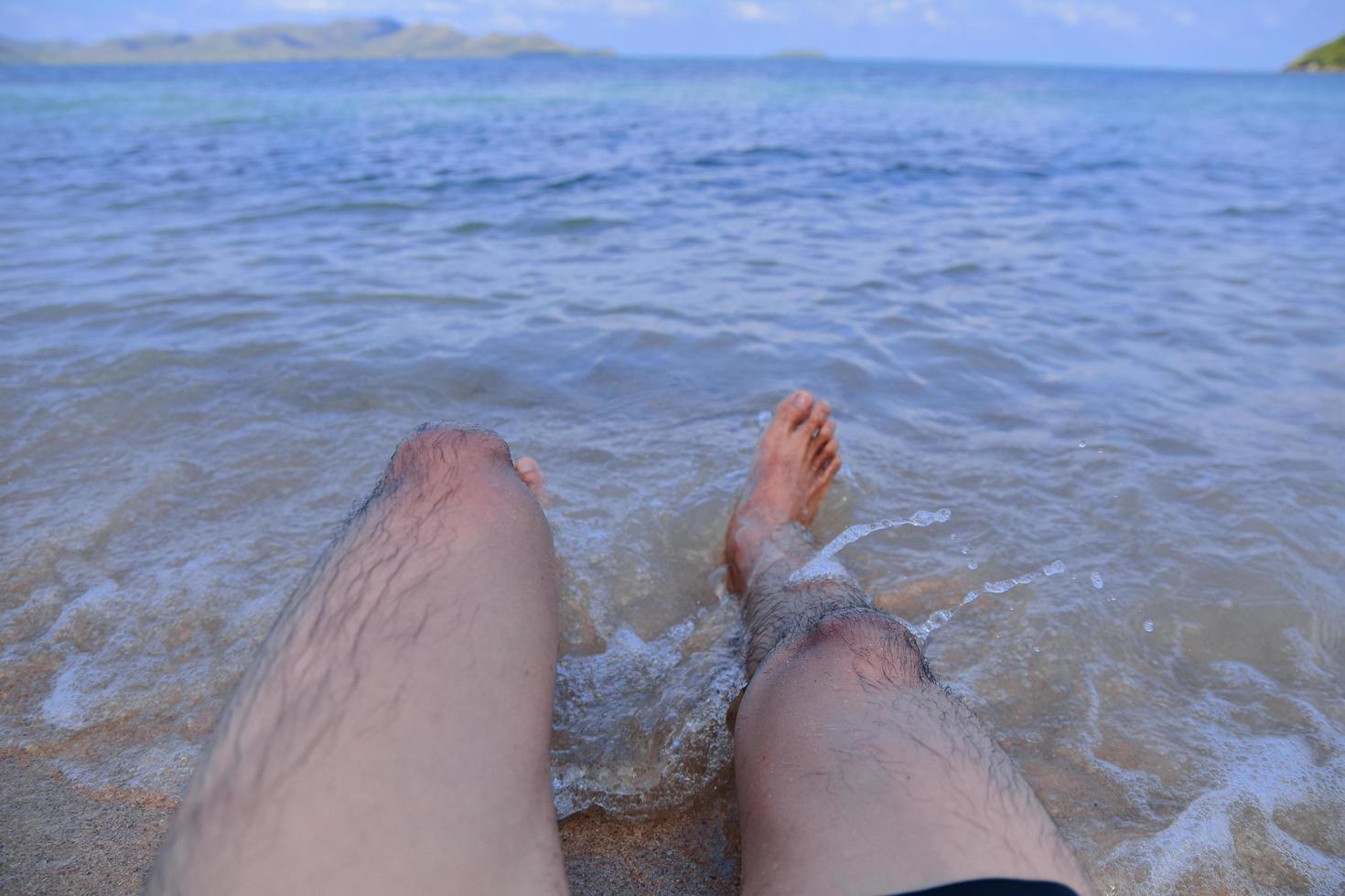 el hombre está en la playa y los pies en el mar foto