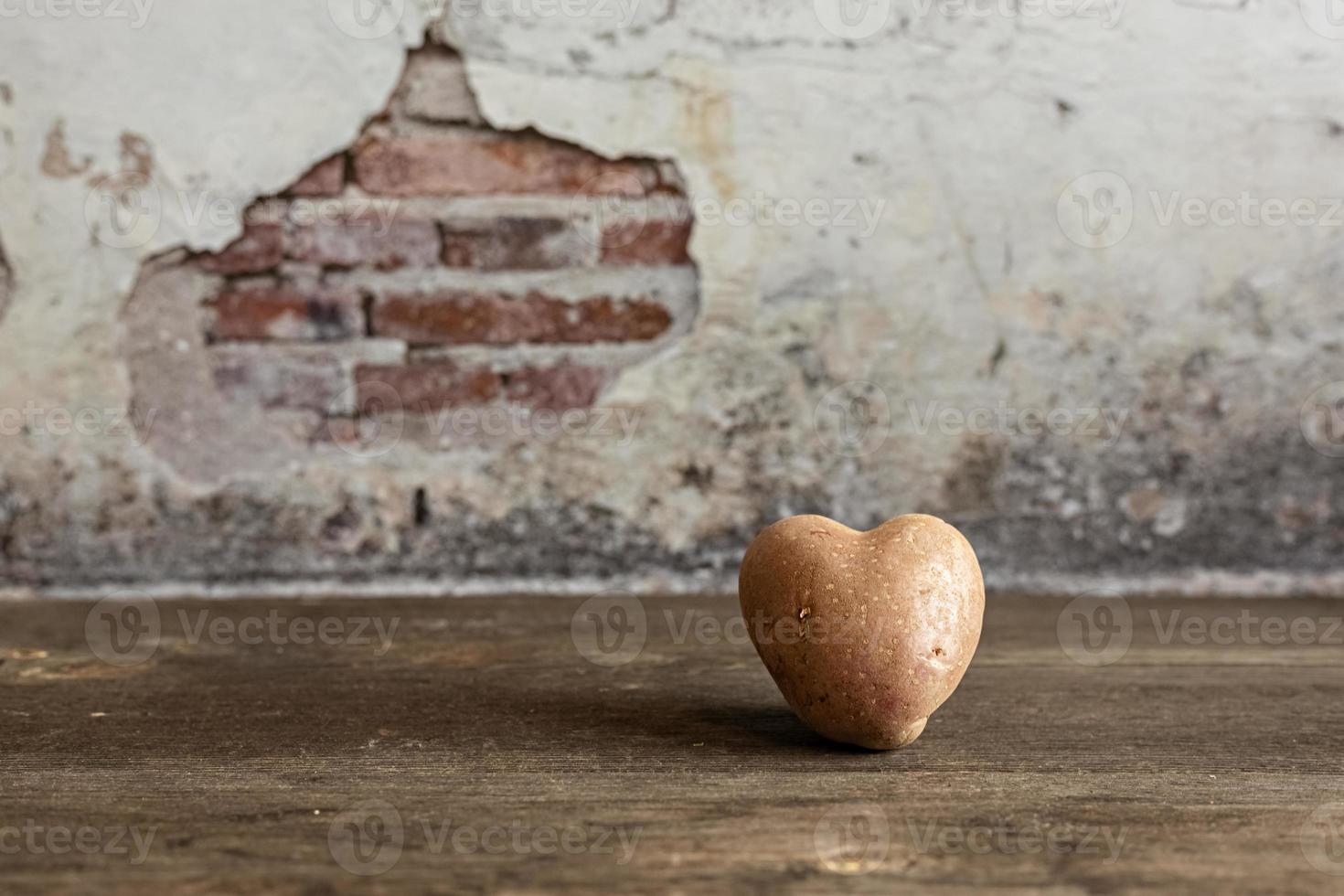 Patata roja en forma de corazón sobre fondo vintage.El concepto de agricultura, cosecha, vegetarianismo. día de San Valentín. comida cuadrada y fea. foto