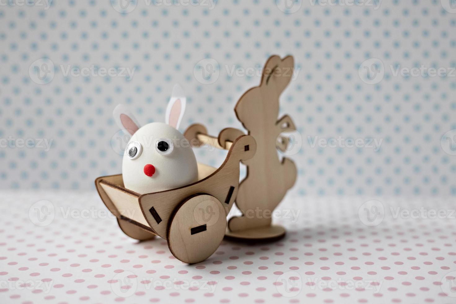 A wooden rabbit carries a cart with an egg with bunny ears. Easter decorations photo