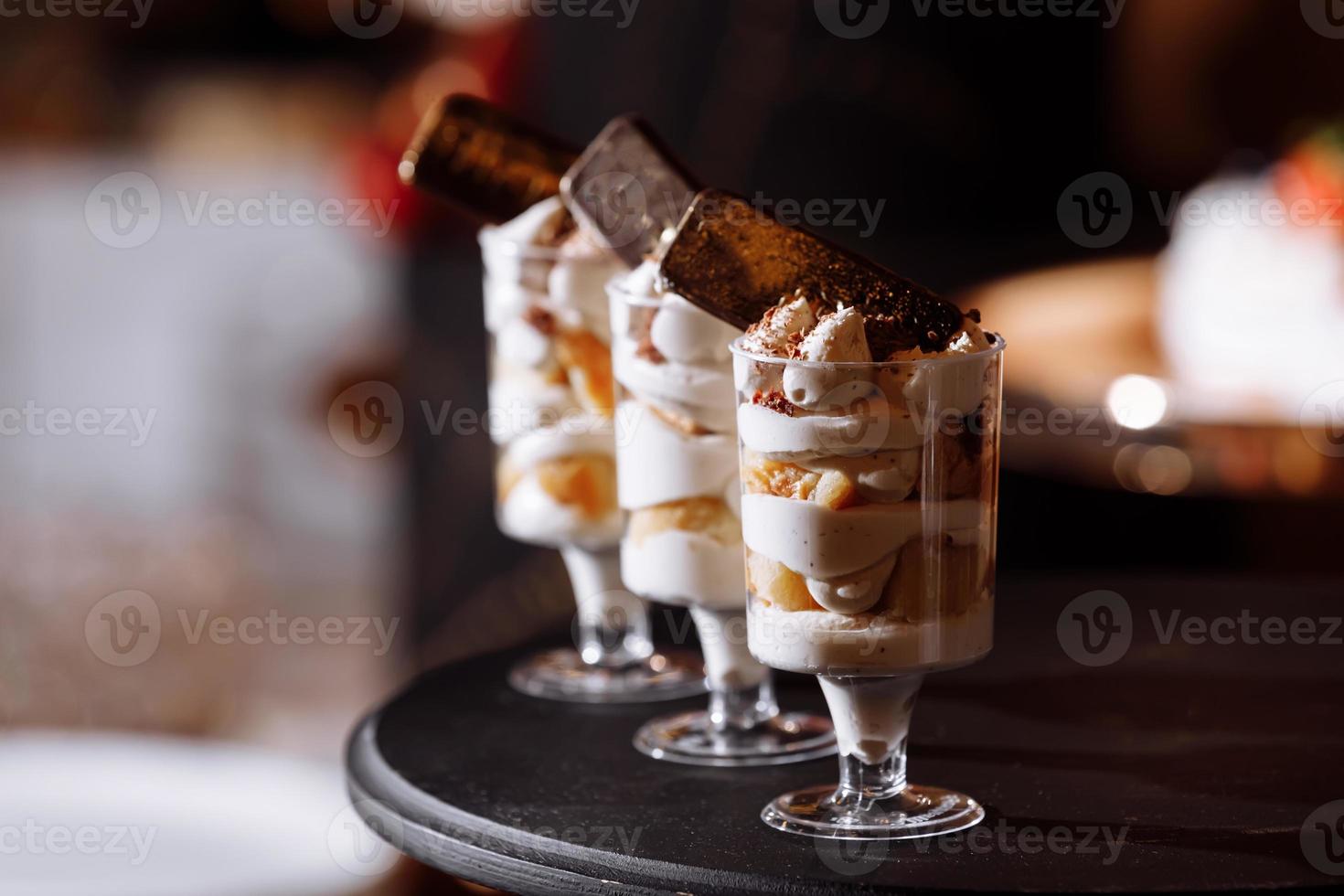 postres de crema con frutos rojos en barra de chocolate. mesa con dulces y golosinas para la recepción de la boda o fiesta de cumpleaños, decoración de mesa de postres. deliciosos dulces en buffet de dulces. enfoque selectivo foto