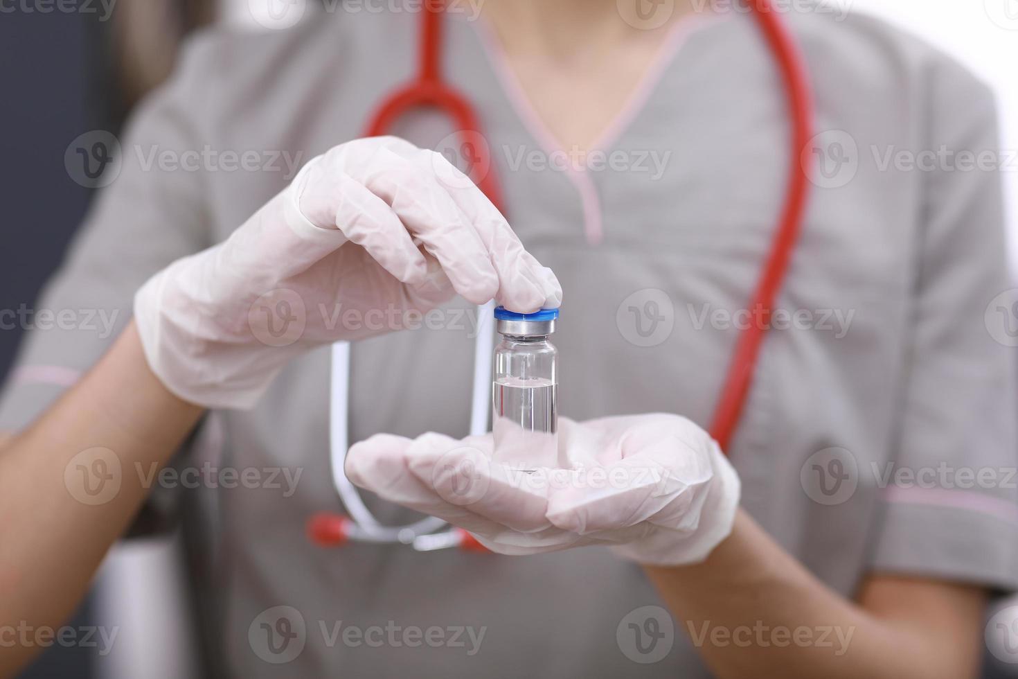 Female doctor with a stethoscope on shoulder holding COVID-19 vaccine. Healthcare And Medical concept. Development and creation of a coronavirus vaccine. photo