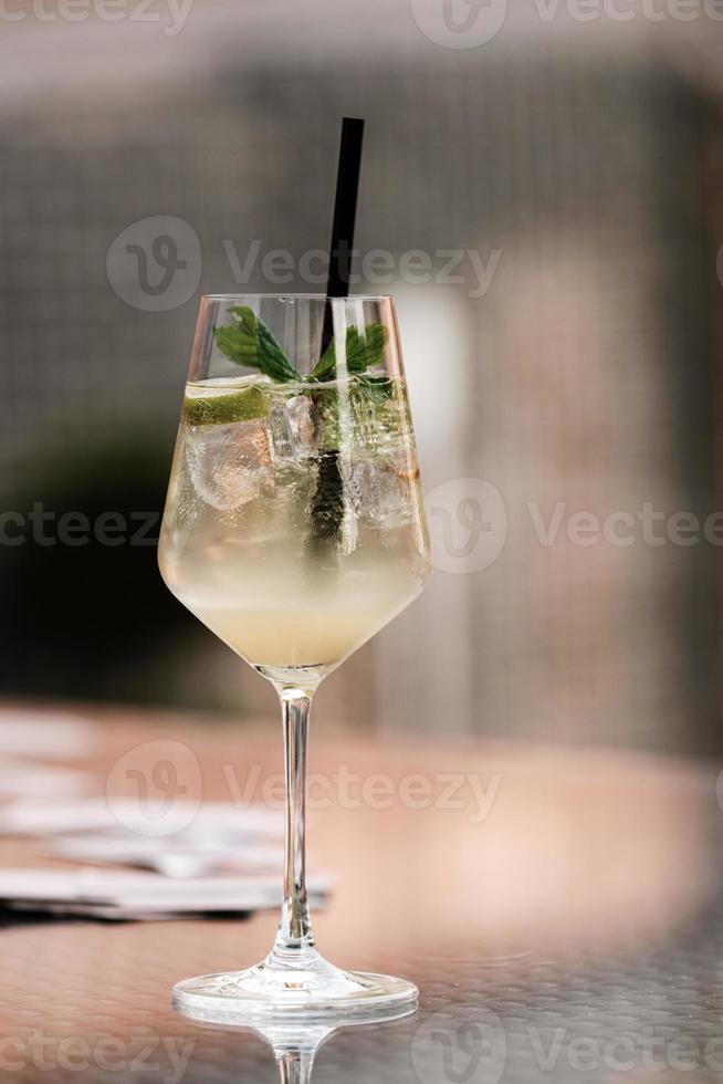 Refreshing Mojito cocktail. Non-alcoholic invigorating drink with lime, mint, ice and cocktail tubes. Carbonated water in a glass with a tube is drunk. Bar drinks series. photo