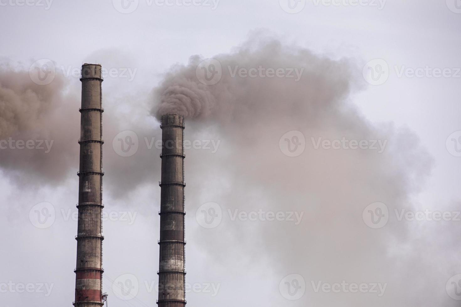 humo de dos chimeneas industriales, tuberías, contra el cielo. calentamiento global. la contaminación del aire. contaminación ecológica. emisiones atmosféricas que contaminan la ciudad. Los residuos industriales son peligrosos para la salud. foto