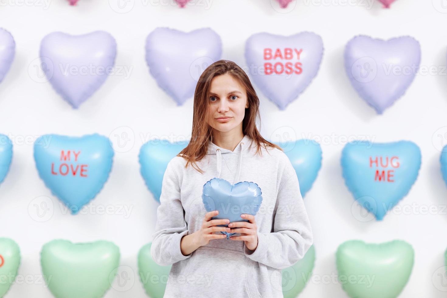 hermosa joven sostiene el globo azul en forma de corazón. muchos corazones de fondo. día de San Valentín. ducha de bebé. enfoque selectivo foto