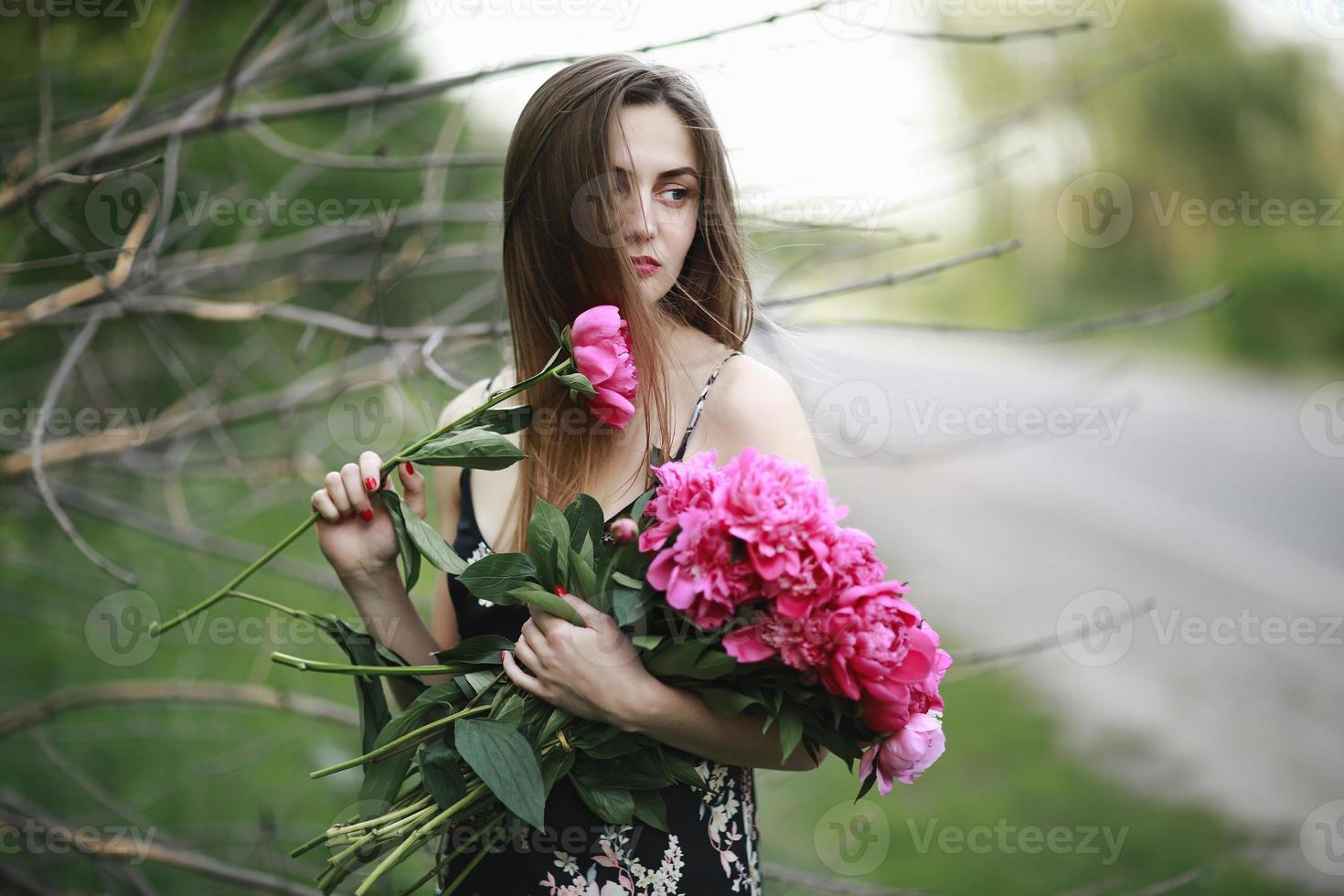 niña abraza un ramo de flores. ramo de peonía. chica en las flores. chica con sombrero presiona un gran ramo de peonías carmesí. cálido día soleado de verano fuera de la ciudad al aire libre foto